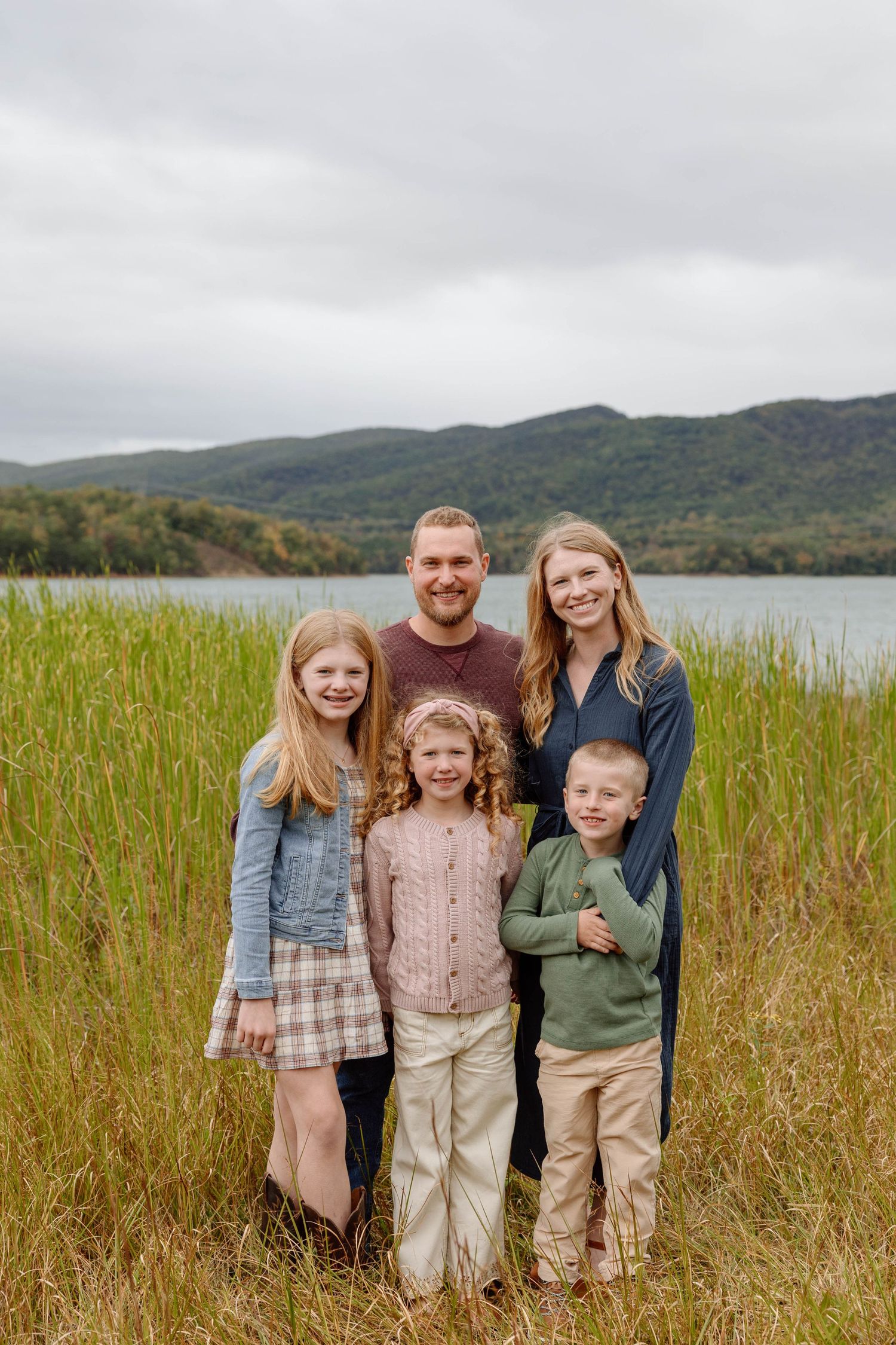 family photo in front of a lake with mountains in the back