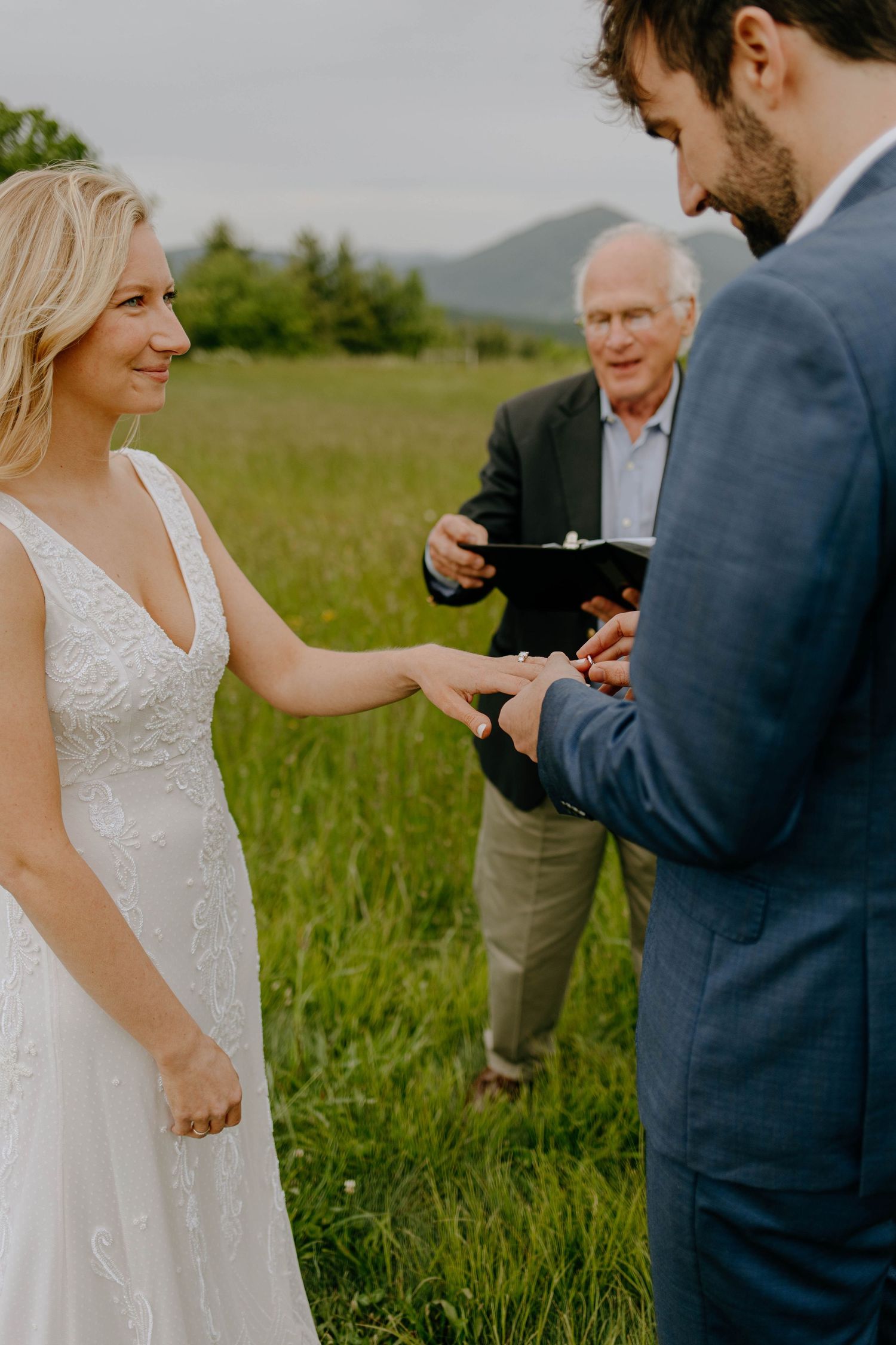 bride and groom exchanging rings in an open field
