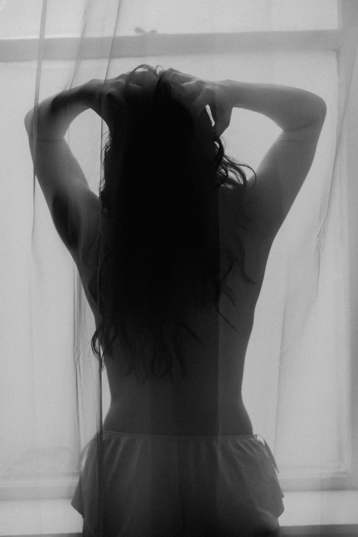 Black and white boudoir, back shot, hands in hair window, natural light, sheer curtain