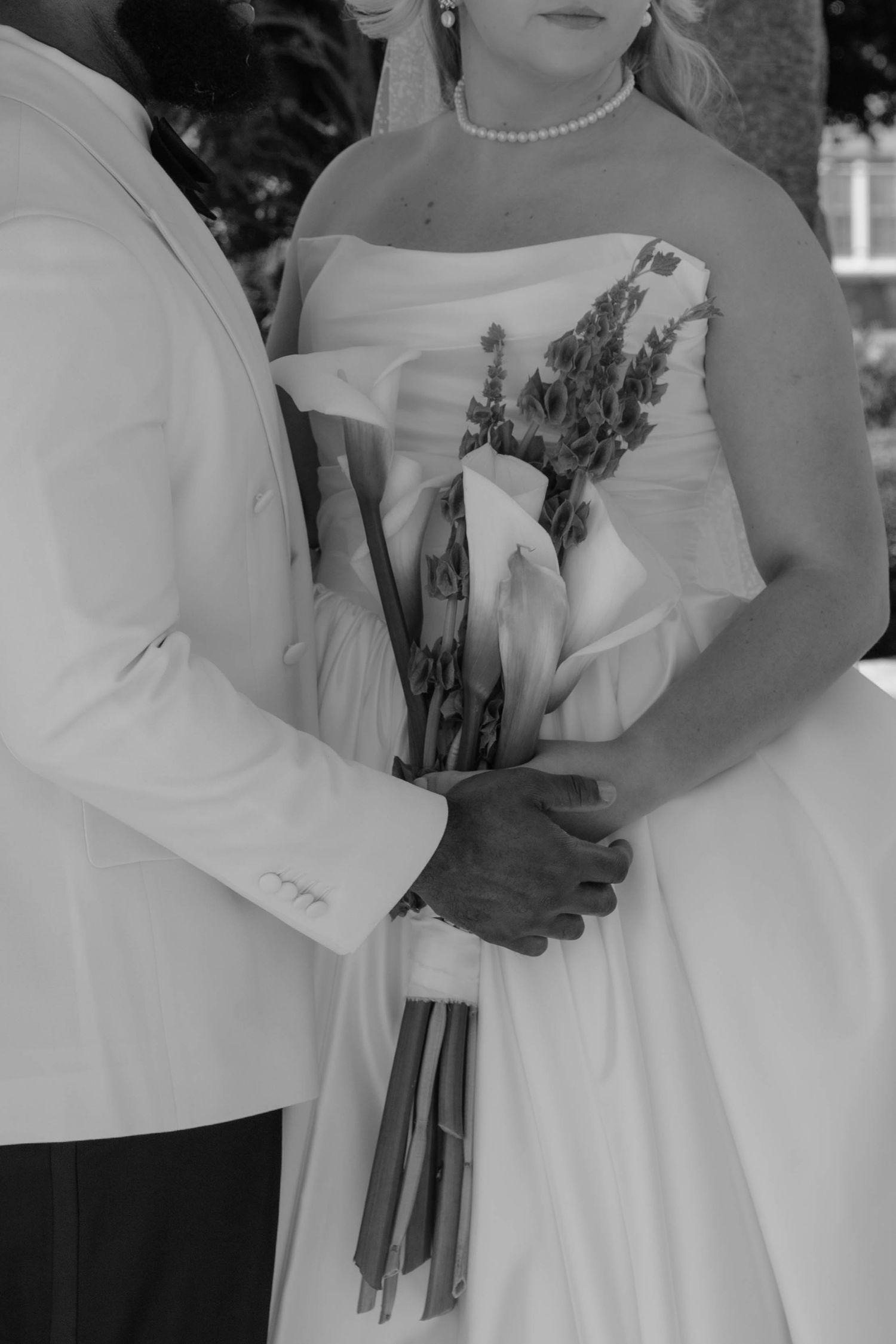 Black and white photo of bride and groom holding a wedding bouquet of calla lilies and lavender.