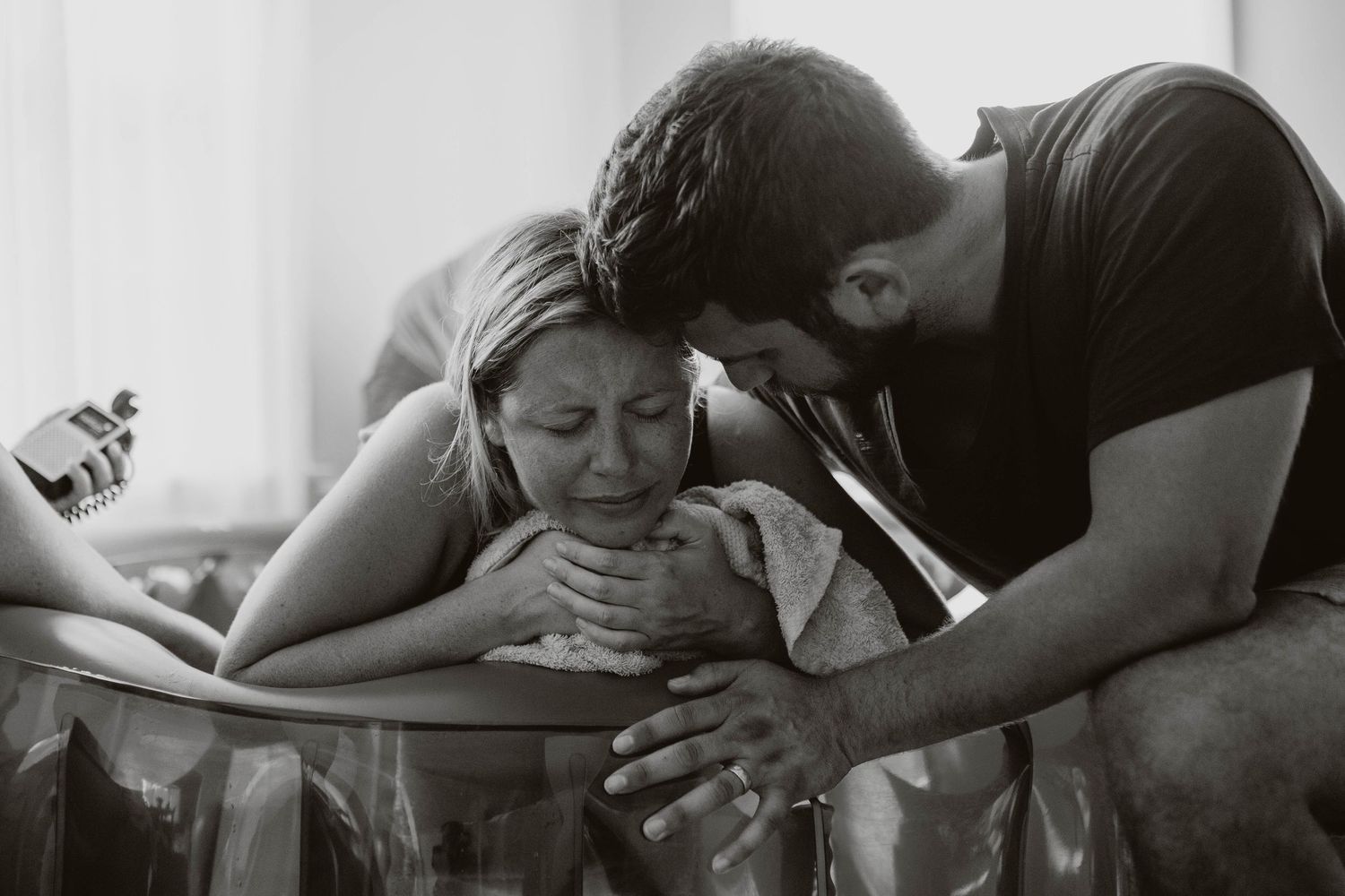 Black and white photo of a couple sharing an emotional moment with their newborn baby during a water birth.