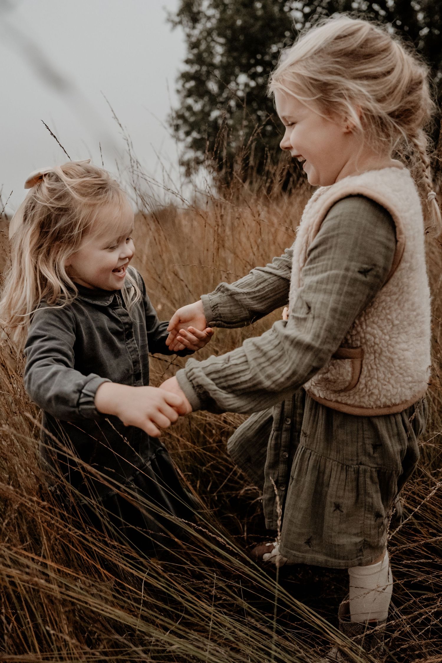 Spelende kinderen die samen aan het dansen zijn tijdens een familie fotoshoot in de natuurlijke omgeving van Leende. Strabrechtse Heide.
