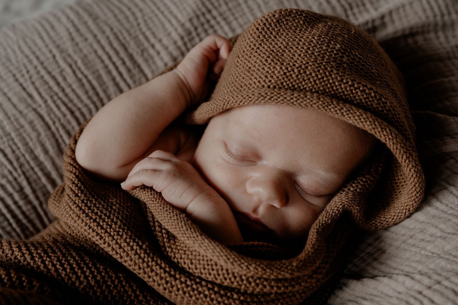 Een slapende newborn van 3 weken oud tijdens een newbornshoot in de intieme sfeer van het eigen huis.