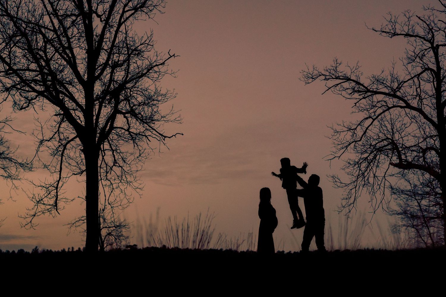 Silhouet van een familie tijdens een fotoshoot in Best, vastgelegd bij zonsondergang tijdens golden hour, met warme goud
