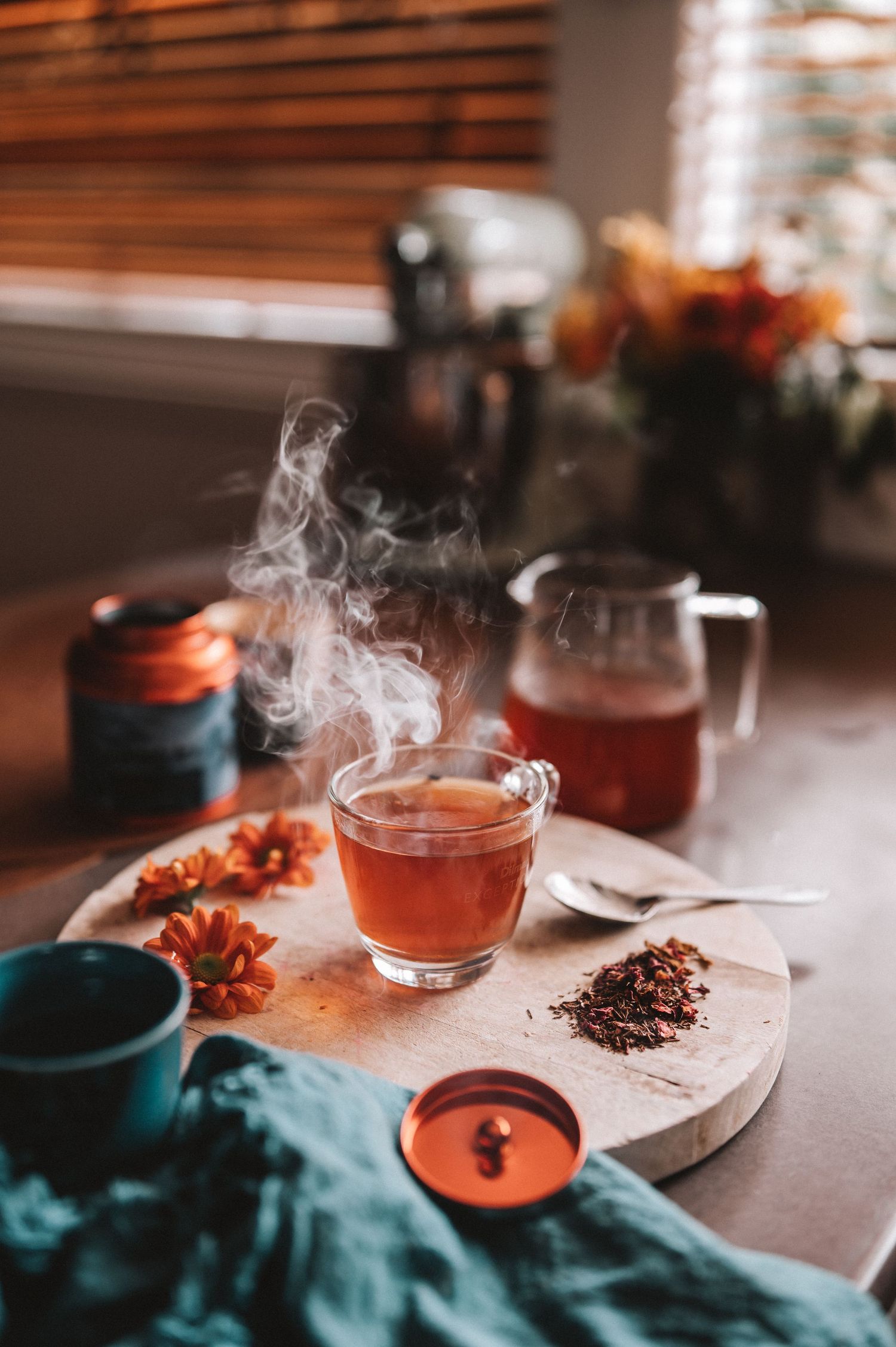 steaming hot cup of tea surrounded by flowers in a moody setting