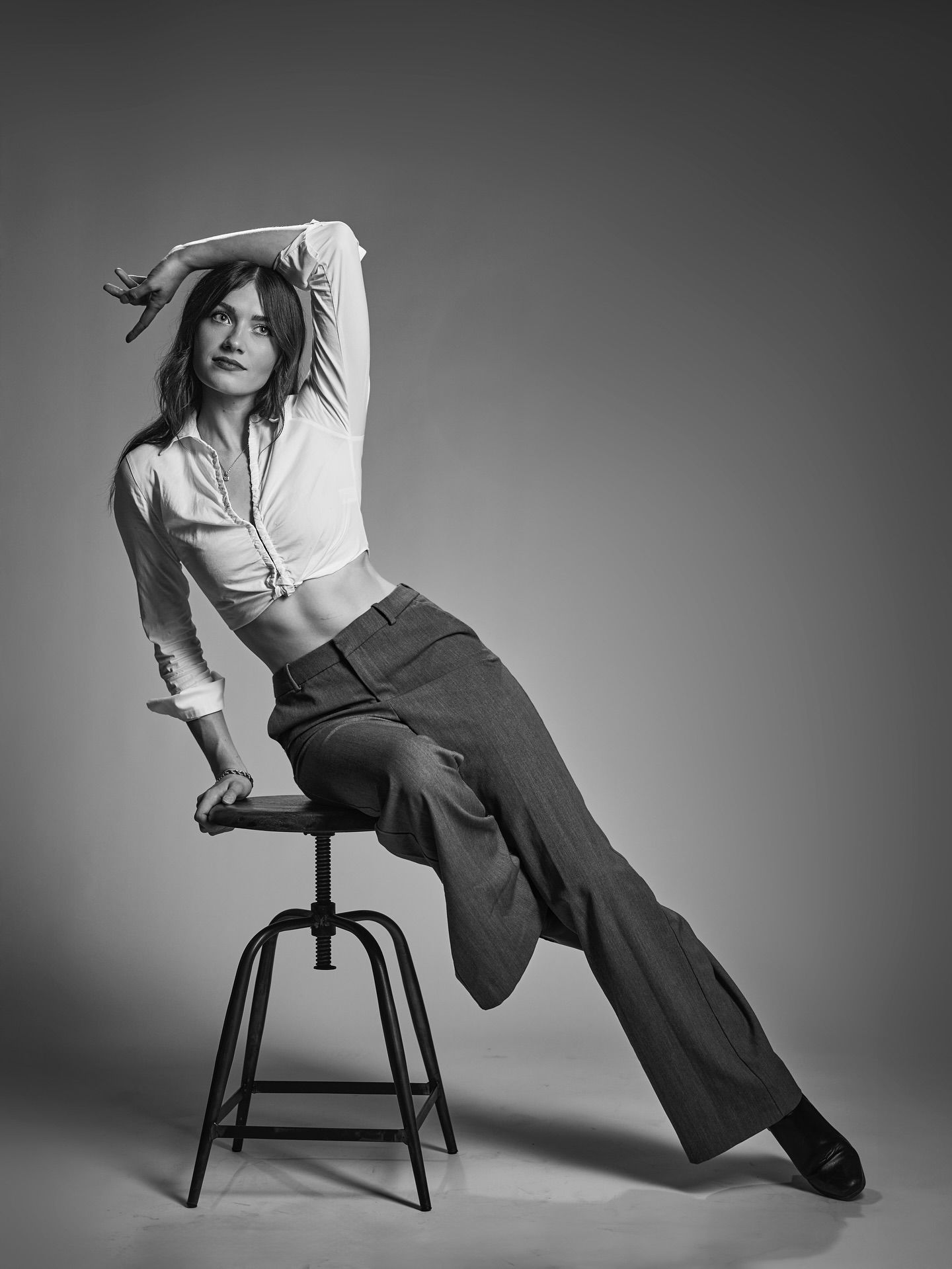 Black and white fashion series showing a figure in wide-leg trousers and white top posing artistically on a chair.