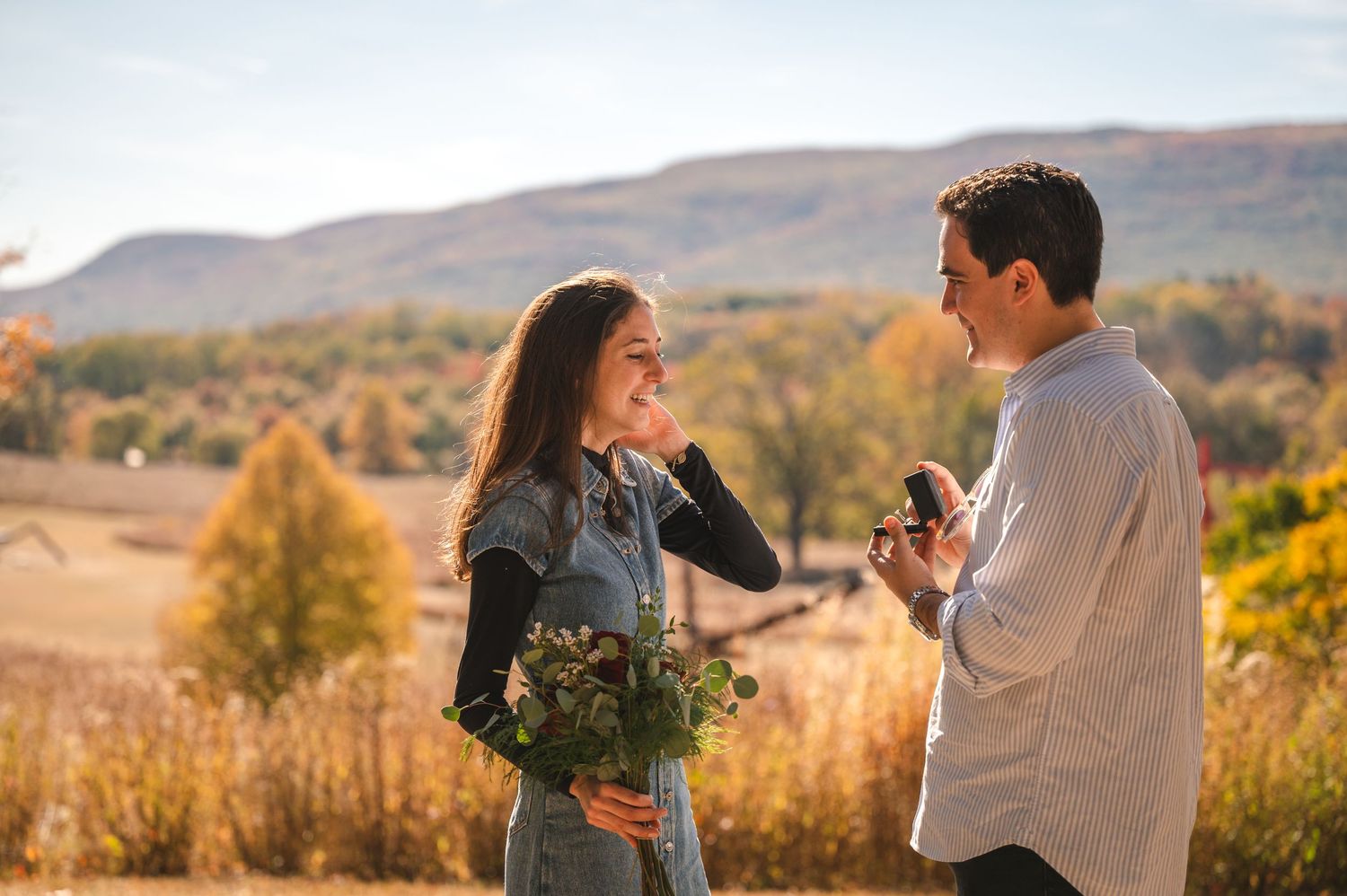 Proposal moment looking at ring in front of autumn trees and mountain views at Storm King Art Center in the Hudson Valley.