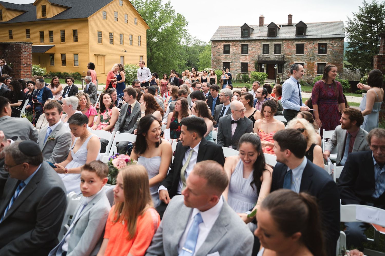 Wedding ceremony celebrated outdoors in front of historic brick buildings at The Ruins at Sassafras in New Lebanon NY, in the Hudson Valley.