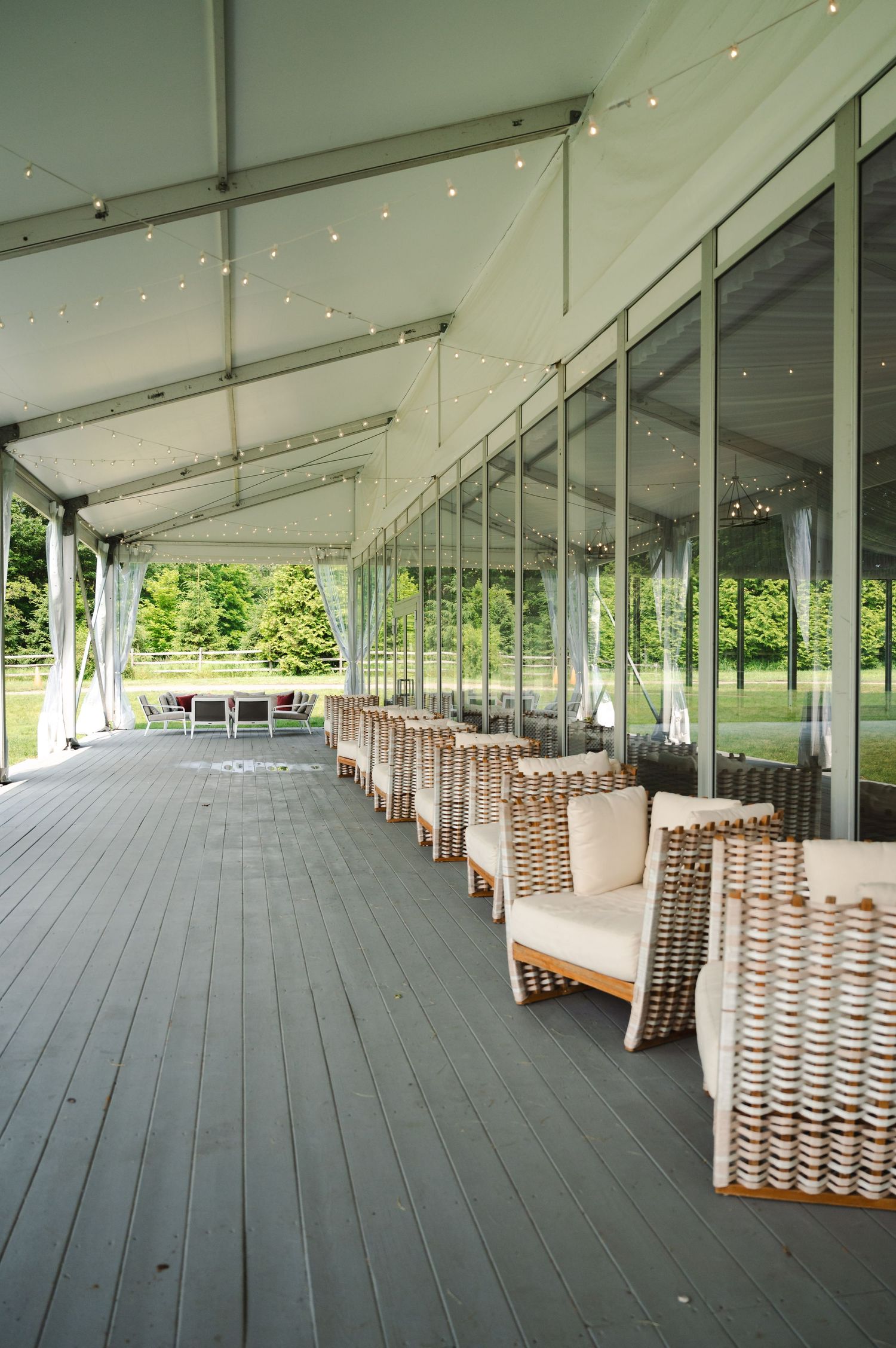 Modern covered outdoor patio with rattan chairs and string lights overlooking a green lawn area at Boscobel in Garrison, NY in Hudson Valley