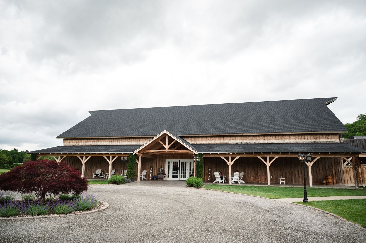 Modern rustic event venue exterior features timber frame construction and circular driveway under cloudy skies at Fortune Valley Manor in NY