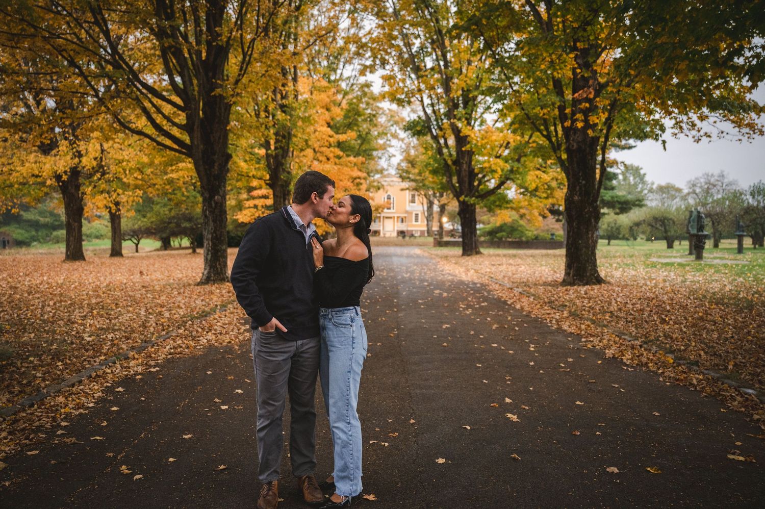 Couple against a path lined with trees and manicured hedges leading to view of mansion estate at Boscobel in Garrison, NY in the Hudson Va