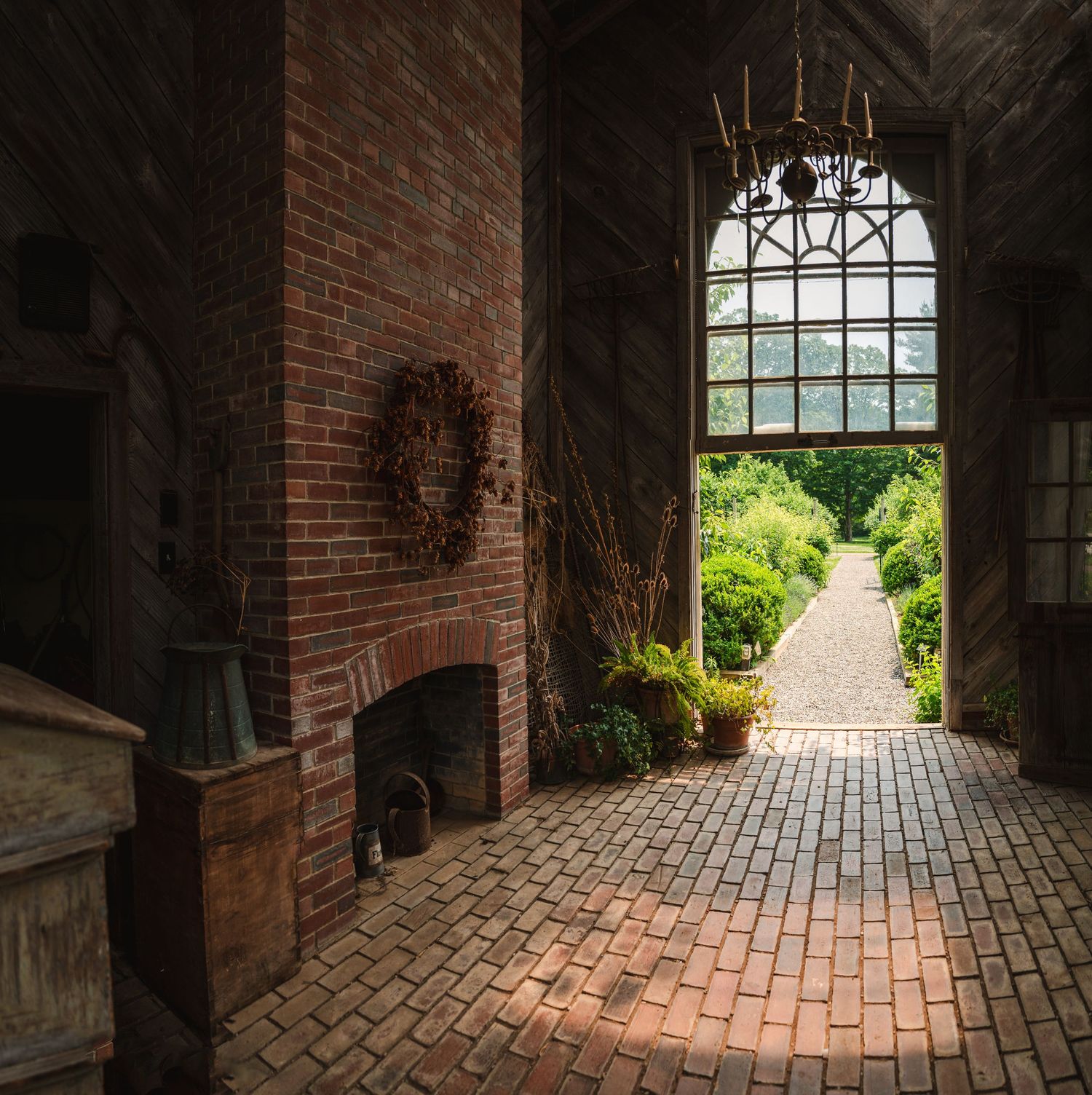 Arched brick doorway opens to a sunny garden path, framed by stone walls and lush greenery at Boscobel in Garrison, NY in the Hudson Valley.