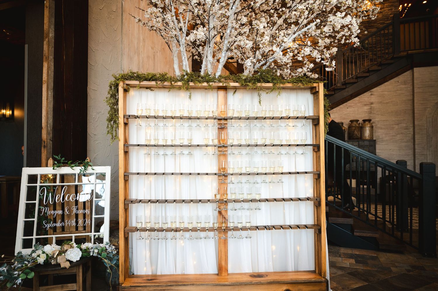 Champagne wall and welcome sign in a rustic farmhouse barn venue at The Barn at Villa Venezia in Middletown, NY the Hudson Valley.