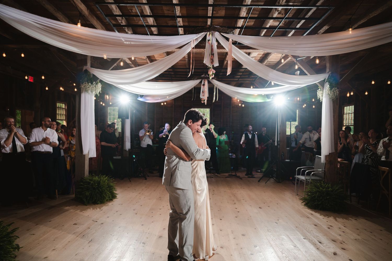 Romantic first dance with couple under elegant white fabric draping at rustic indoor wedding reception at the Ruins at Sassafras in New York