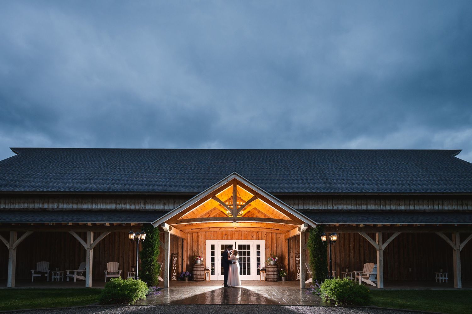 Hudson Valley wedding couple portrait in illuminated barn venue with dramatic stormy sky at Fortune Valley Manor in Saugerties, NY.