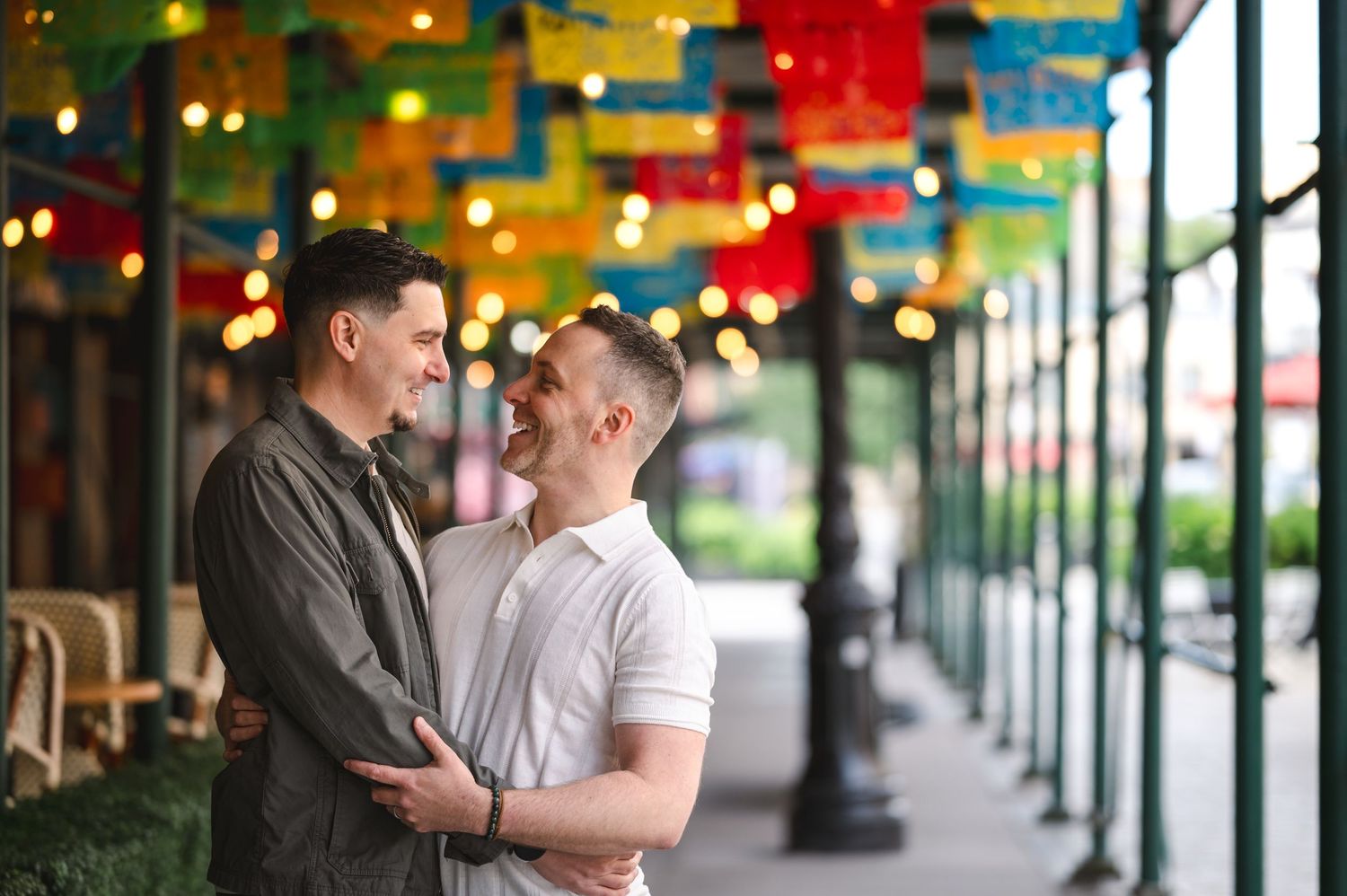 Engagement photo of couple sharing a romantic moment under colorful lanterns hanging at an outdoor restaurant patio in Manhattan, NYC.