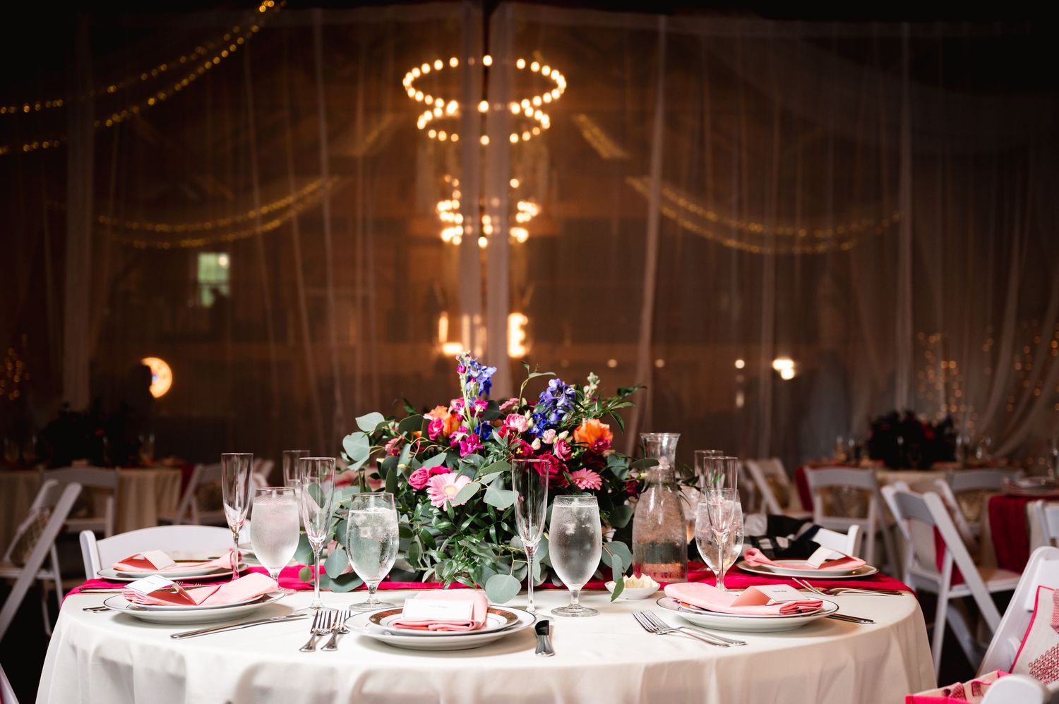 Elegant wedding reception table setting with floral centerpiece and chandelier in barn at Fortune Valley Manor in Saugerties, NY.