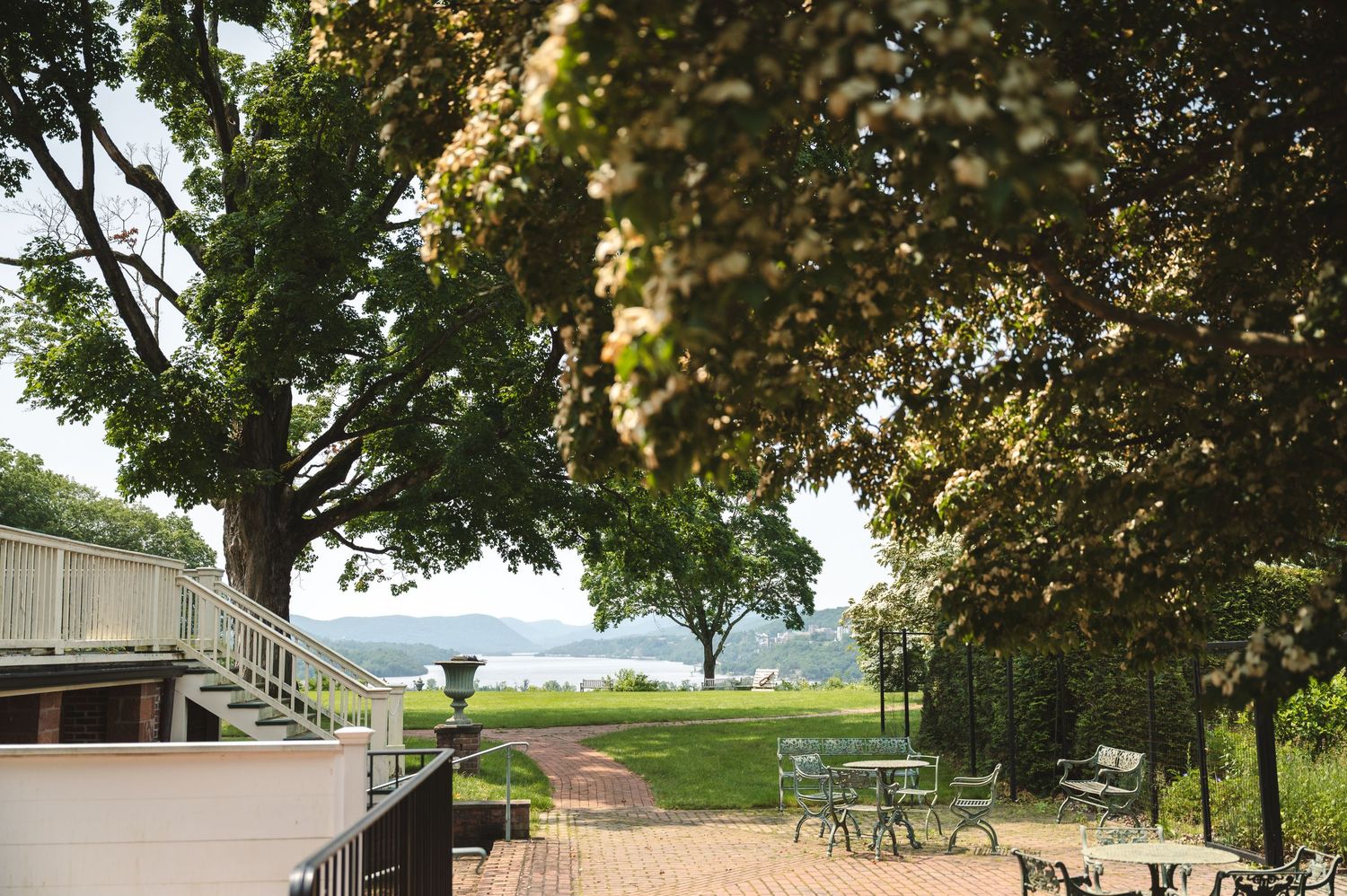 Peaceful lakeside patio with Adirondack chairs under mature trees offering a tranquil water view.