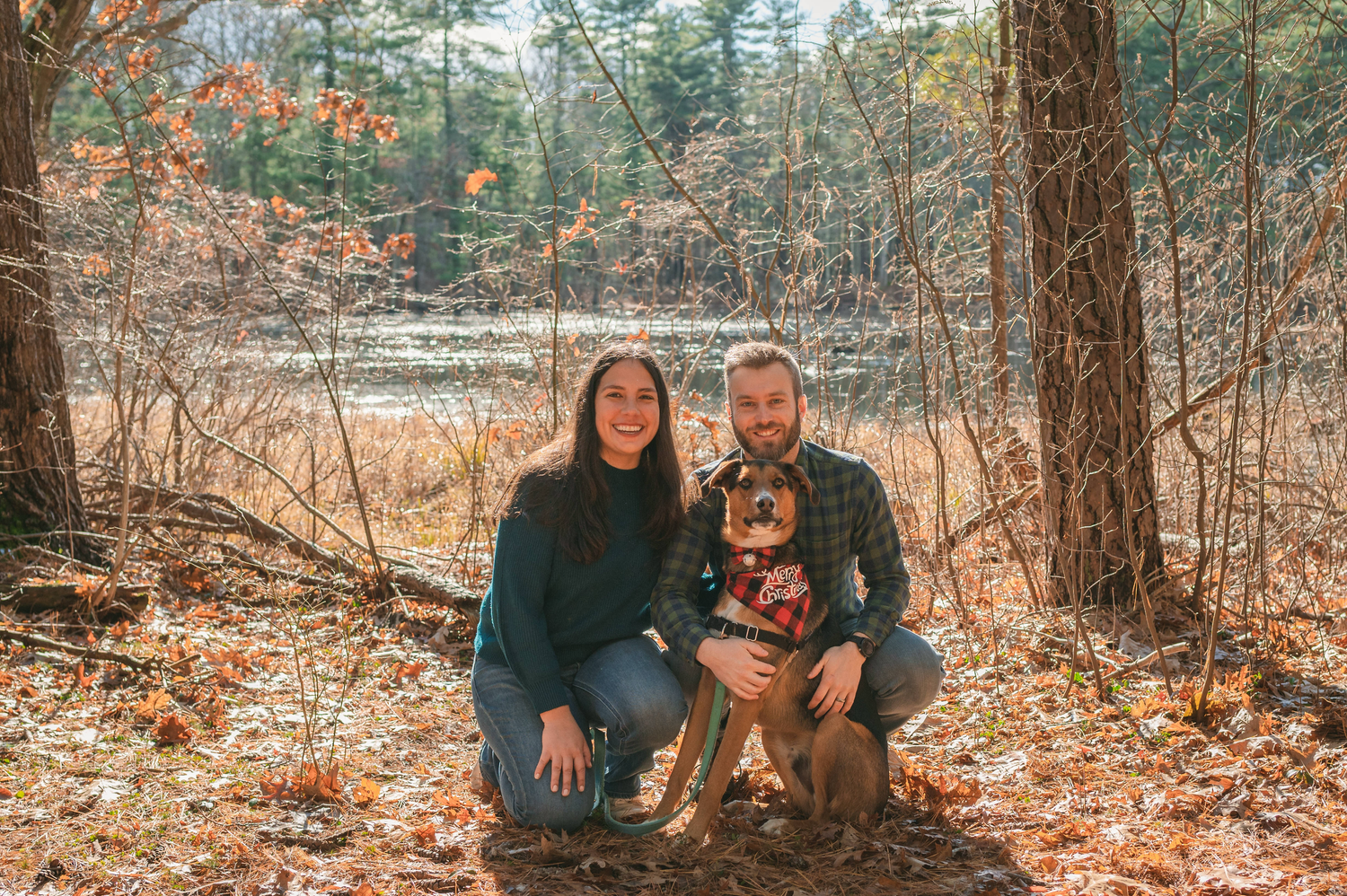 Matthew Rigby with his dog and wife in autumn forest in Massachusetts smiling for family portrait.