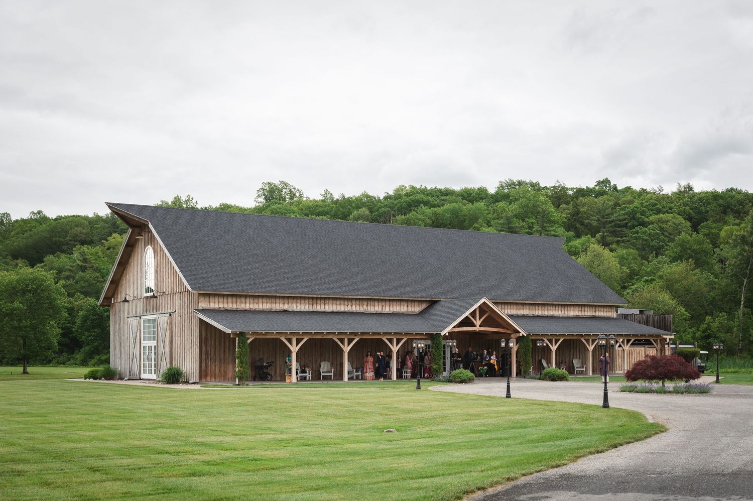 Modern barn with beams, timber siding, and tall windows with rolling green lawns and natural landscaping at Fortune Valley Manor in New York