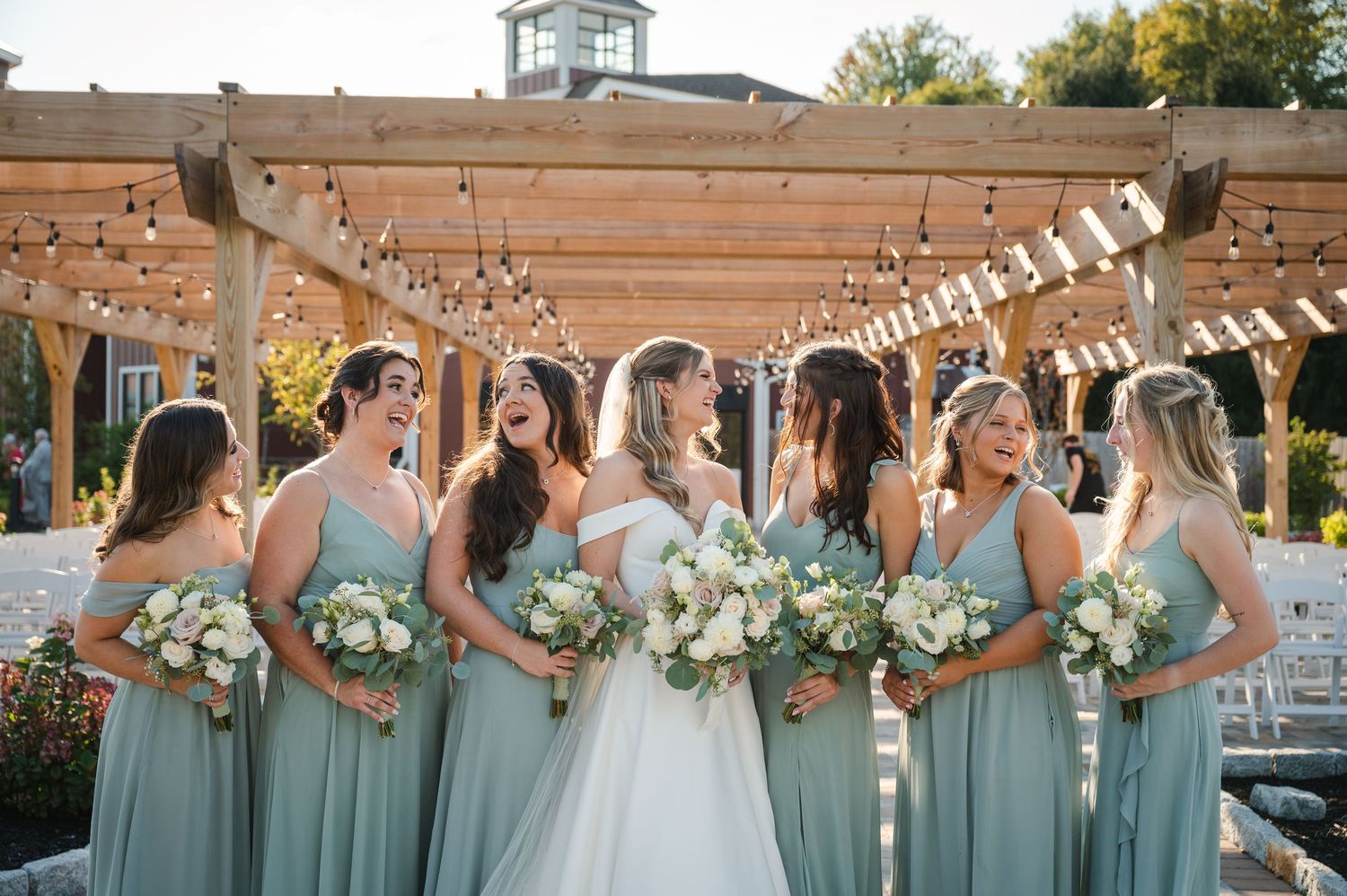 Group photo of bridesmaids and bride in front of trellis outdoor paved patio ceremony space The Barn at Villa Venezia in Middletown, NY.