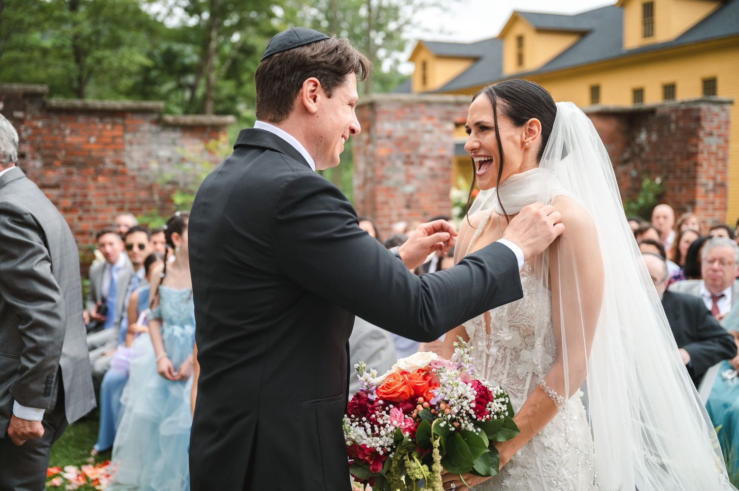 A couple shares a joyful moment together with veil during garden wedding ceremony at The Ruins at Sassafras in the Hudson Valley.