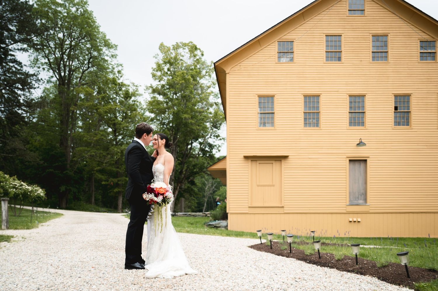 Bride and groom share a romantic moment on a gravel path outside the Chair Factory at The Ruins at Sassafras in the Hudson Valley, NY.