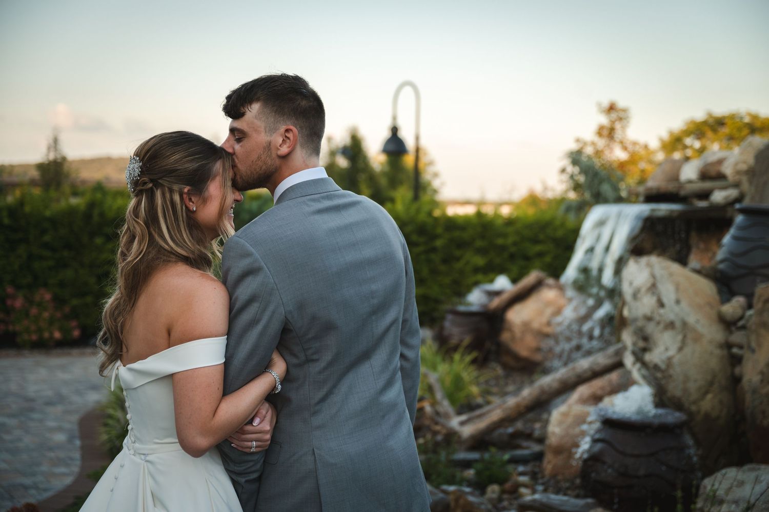 Wedding portrait couple during golden hour surrounded by greenery on patio with waterfall at The Barn at Villa Venezia in Middletown, NY.