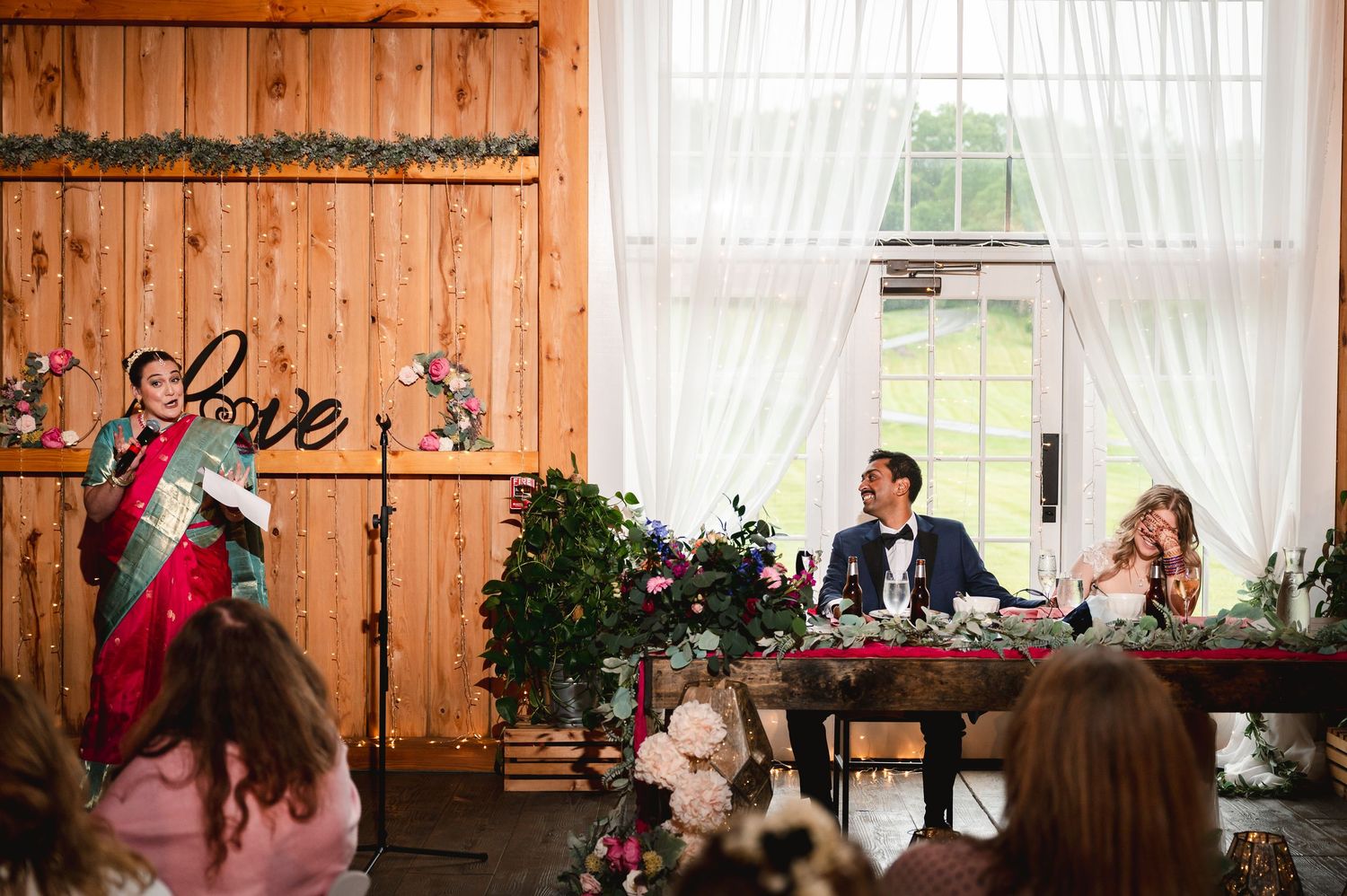 Joyful reception moment with laughter during speeches in rustic barn wedding venue at Fortune Valley Manor in Saugerties, NY, Hudson Valley.