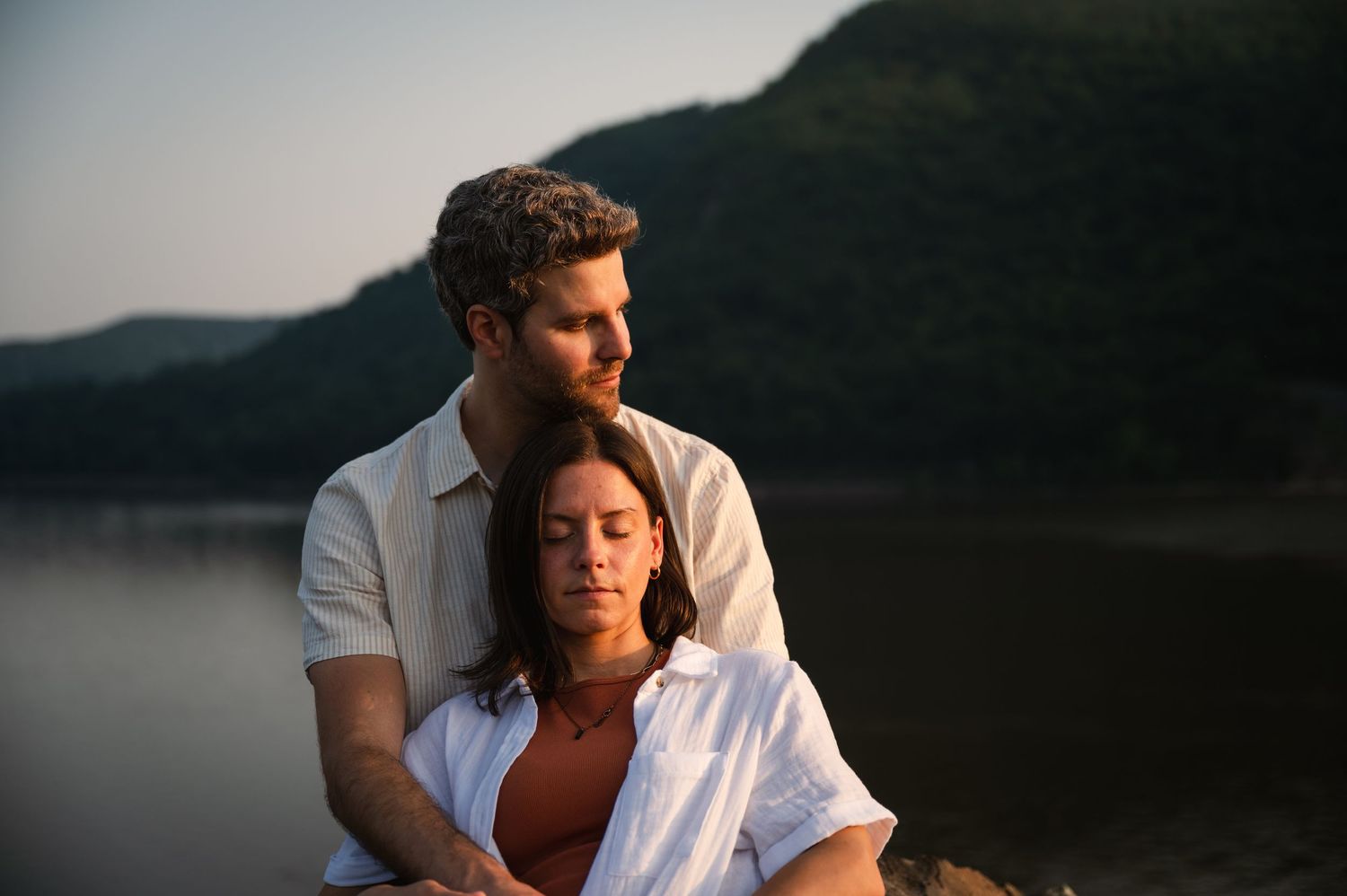 A series of moody seaside portraits showing a person in casual white clothing against a dark water backdrop during sunset.