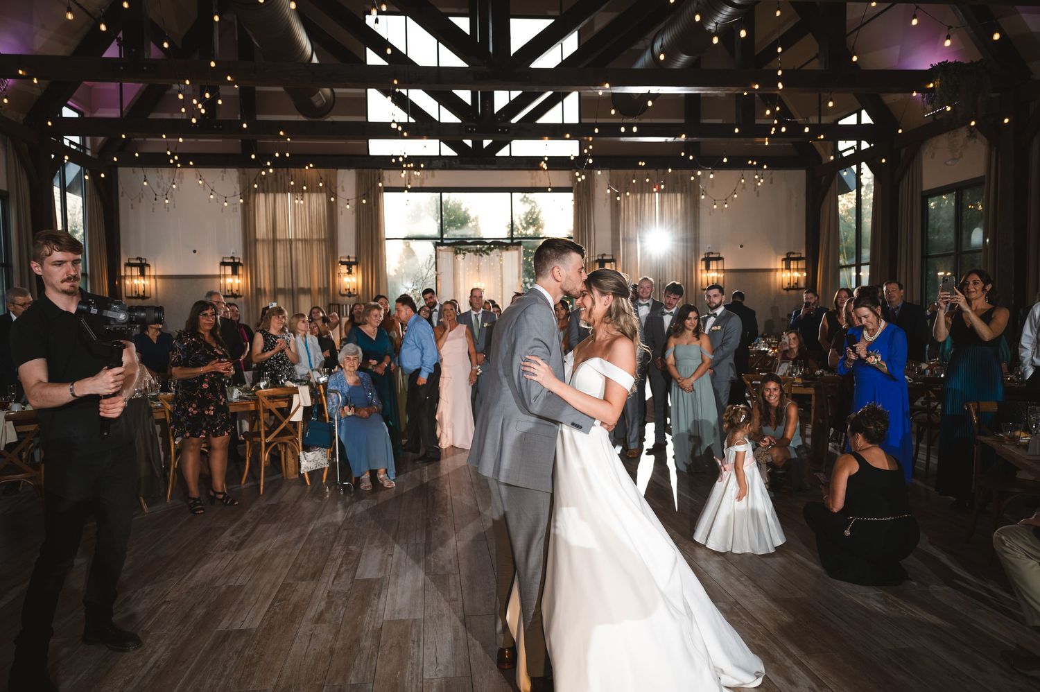 A romantic wedding couple laughing during first dance while guests watch in the background at The Barn at Villa Venezia in Middletown, NY.