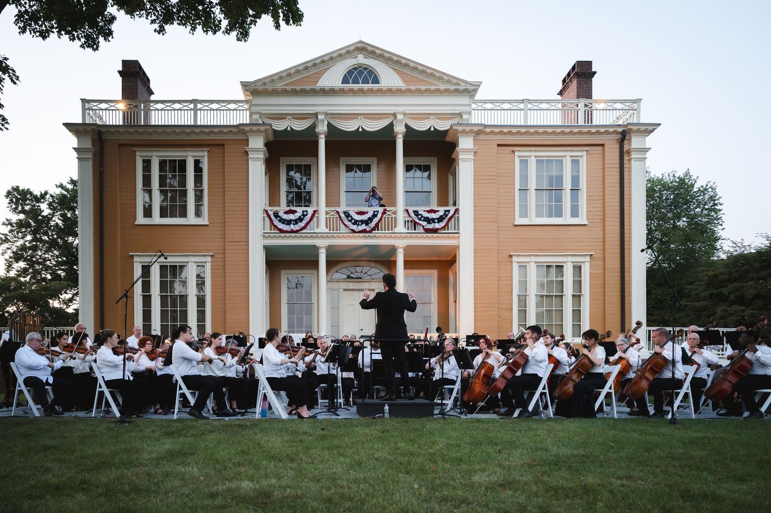Historic Boscobel House mansion with columns hosts an elegant outdoor dinner party on the expansive lawn in Garrison, NY in Hudson Valley.