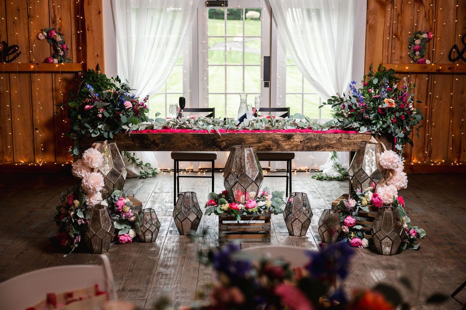 Elegant rustic wedding reception table decorated with pink flowers and crystal vases in a wooden barn venue at Fortune Valley Manor, NY.