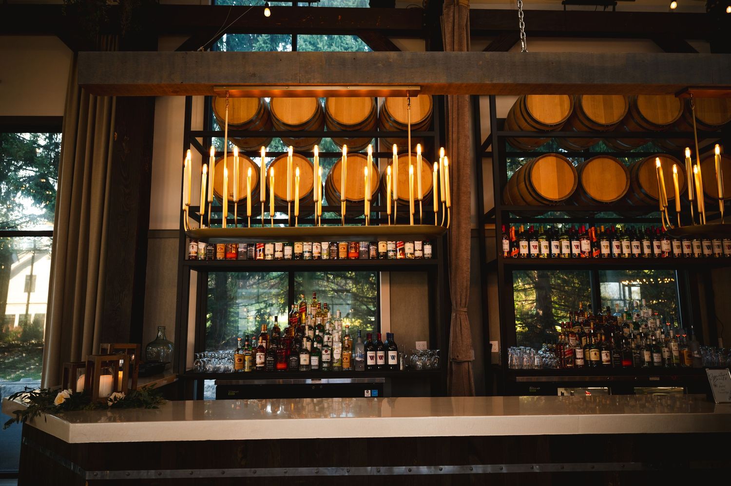 Elegant wedding bar set up with glowing candles and wine barrels above bar in background  of reception Barn at Villa Venezia Middletown, NY.