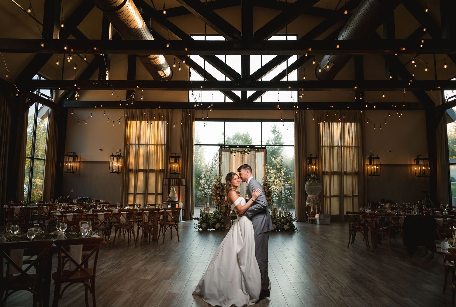 Flash portrait of smiling couple in rustic barn reception space with exposed beams and string lights at The Barn at Villa Venezia Middletown