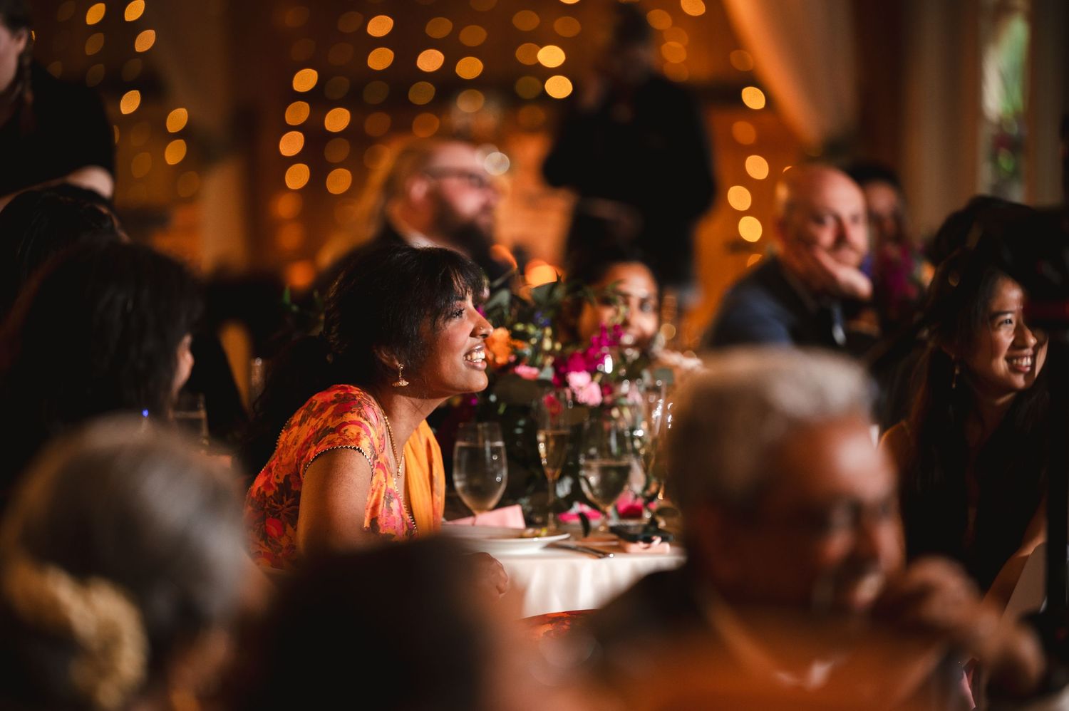 Warm ambient lighting illuminates a darkened reception hall filled with guests enjoying best man speeches at Fortune Valley Manor Saugerties
