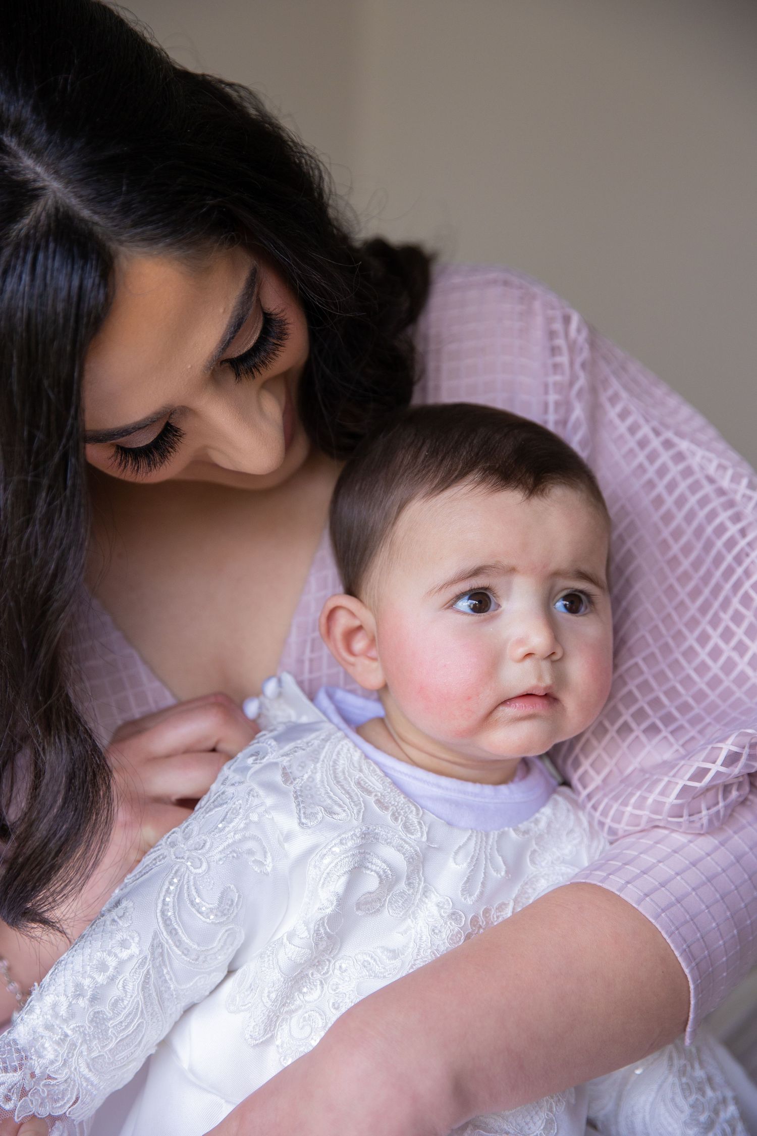 An intimate portrait of a baby in white christening attire being held lovingly.