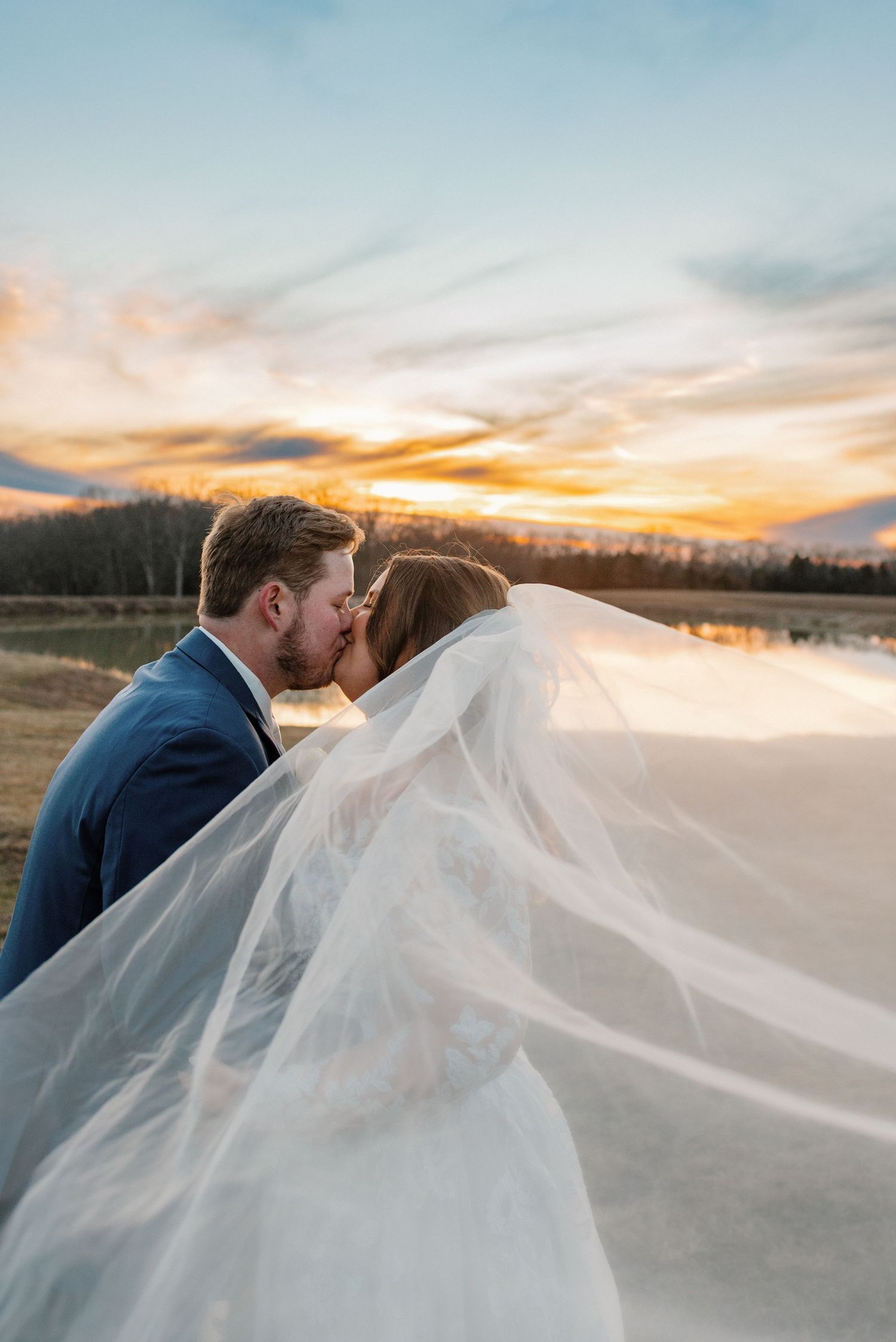Romantic sunset photo with flowing veil creating dramatic effect over water.