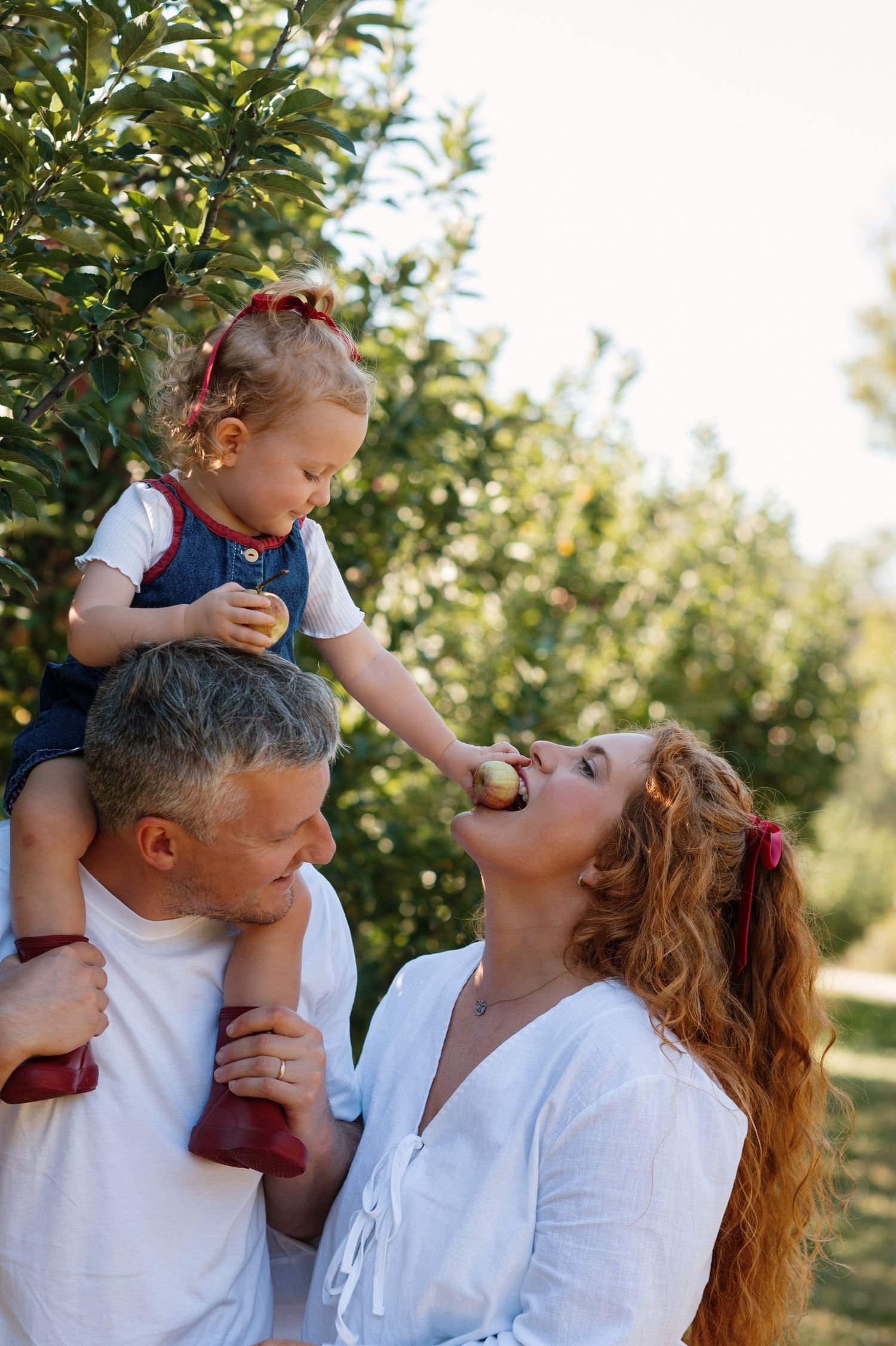 Family shares joyful moments together in an apple orchard on a sunny afternoon.