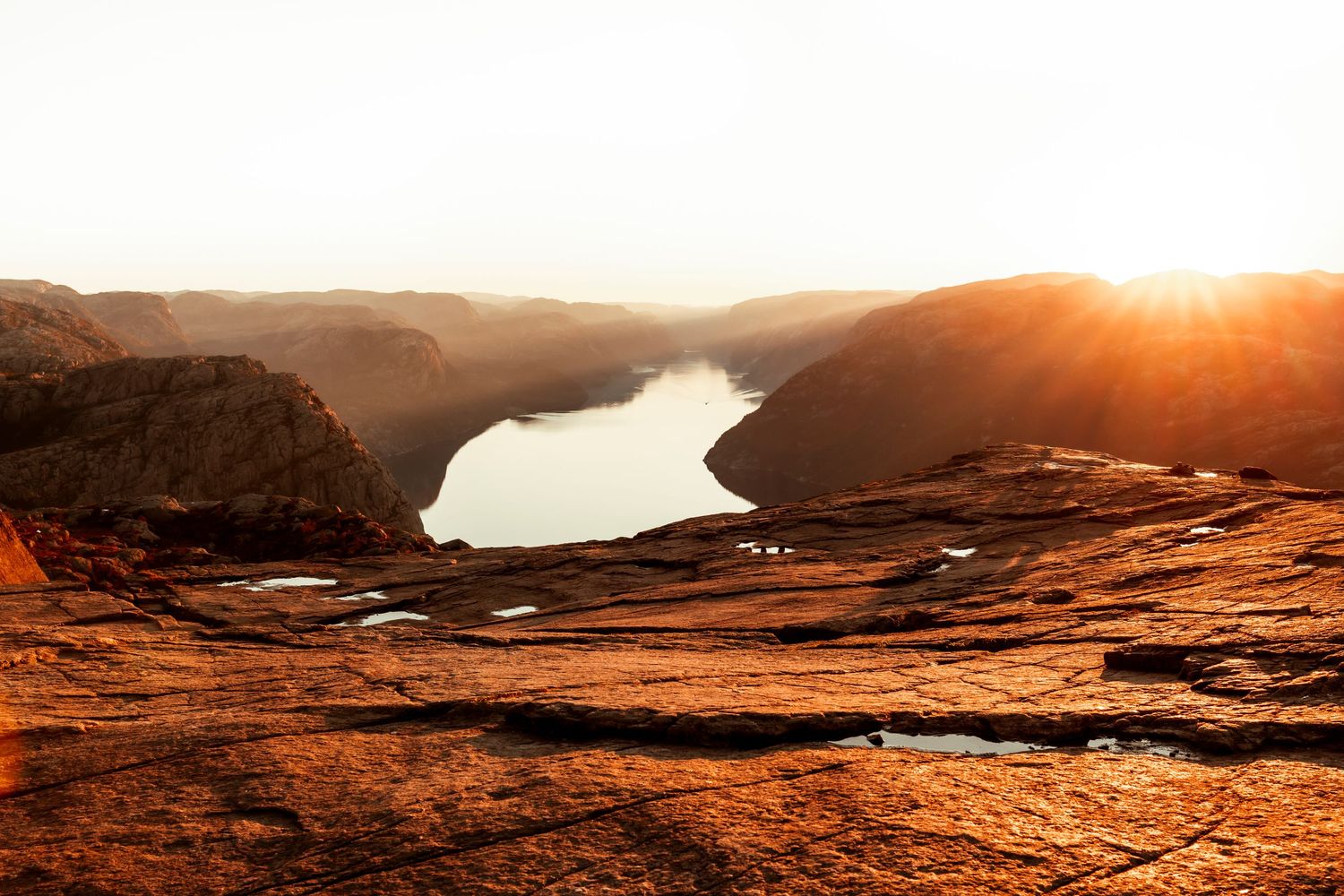 Majestic sunset over Lake Powell with red desert cliffs and winding river through sandstone canyon landscape.