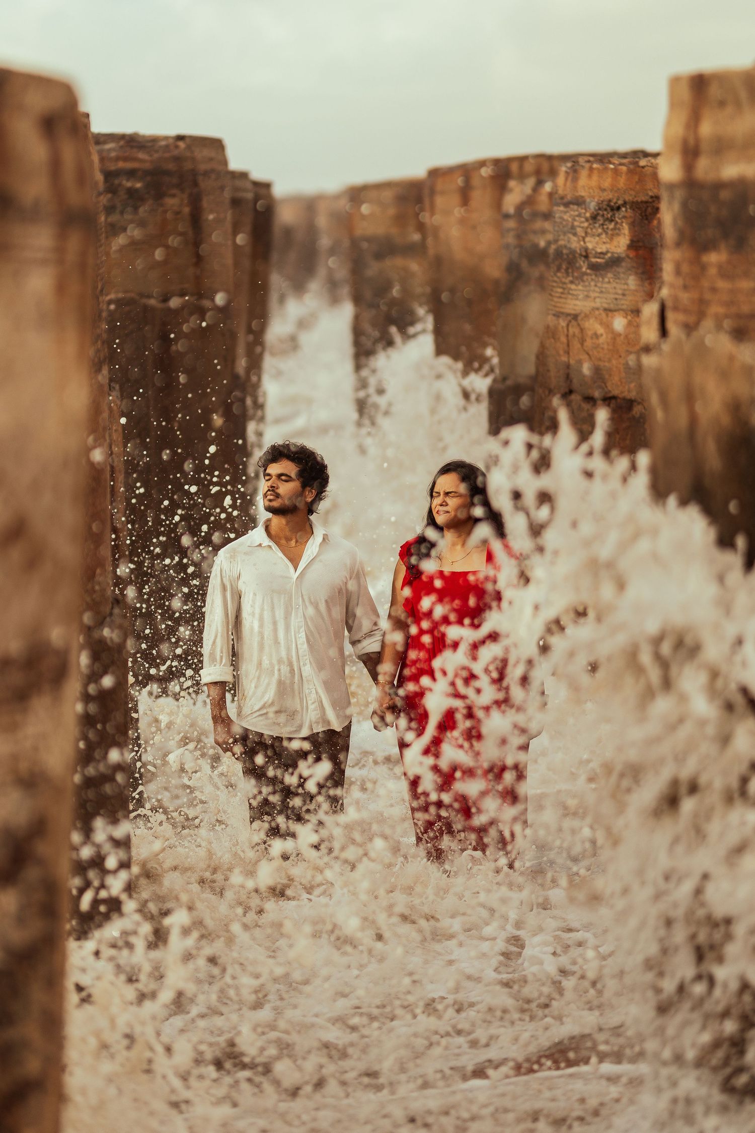 People playing in splashing water against an old weathered wall backdrop.