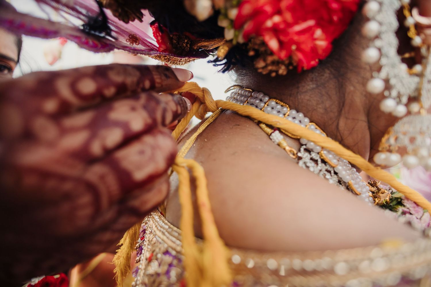 Close-up detail of traditional Indian wedding jewelry and henna decorated hands during a ceremony.