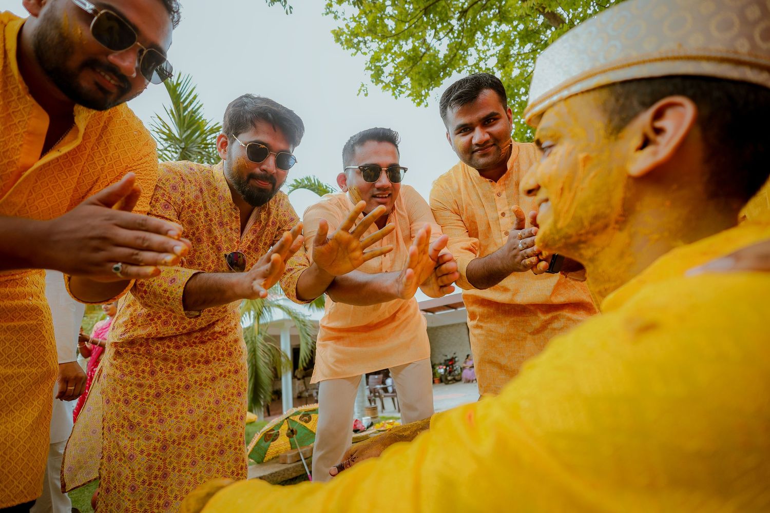 A group of people wearing yellow shirts and sunglasses celebrate at an outdoor gathering with drinks.