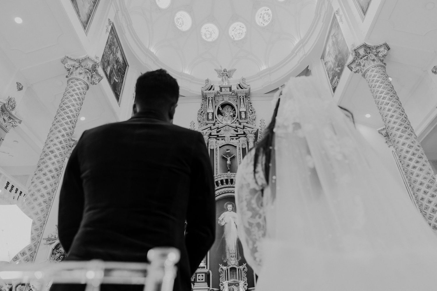 Black and white wedding photography showing elegant decor with hanging lights and floral arrangements.