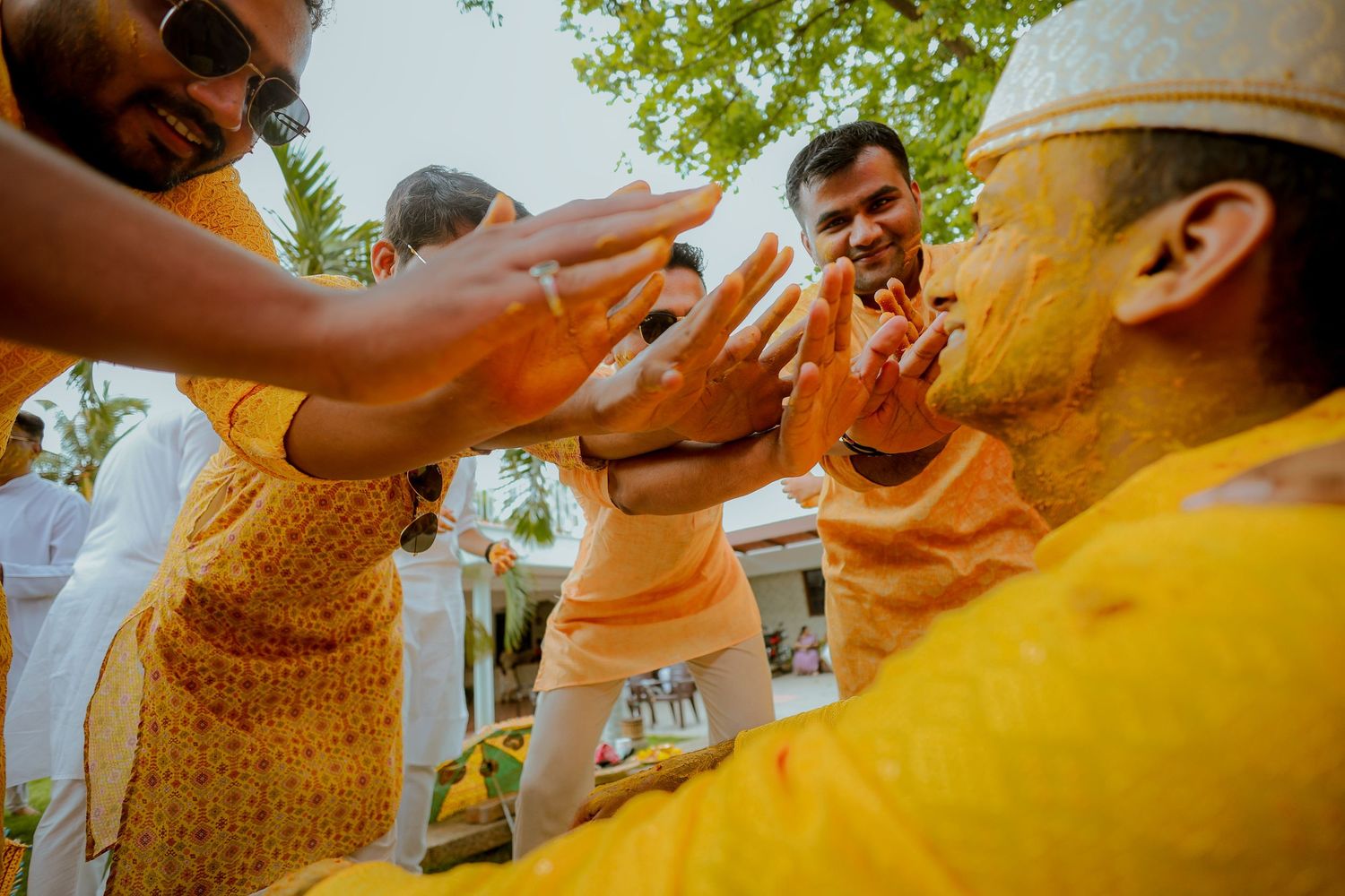 People perform a traditional Indian wedding ritual with turmeric powder during an outdoor ceremony.