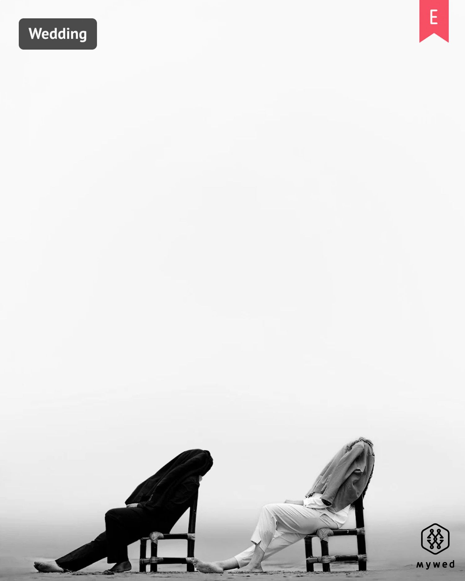 Black and white wedding photo of bride and groom sitting back-to-back on chairs, heads bowed in artistic pose.