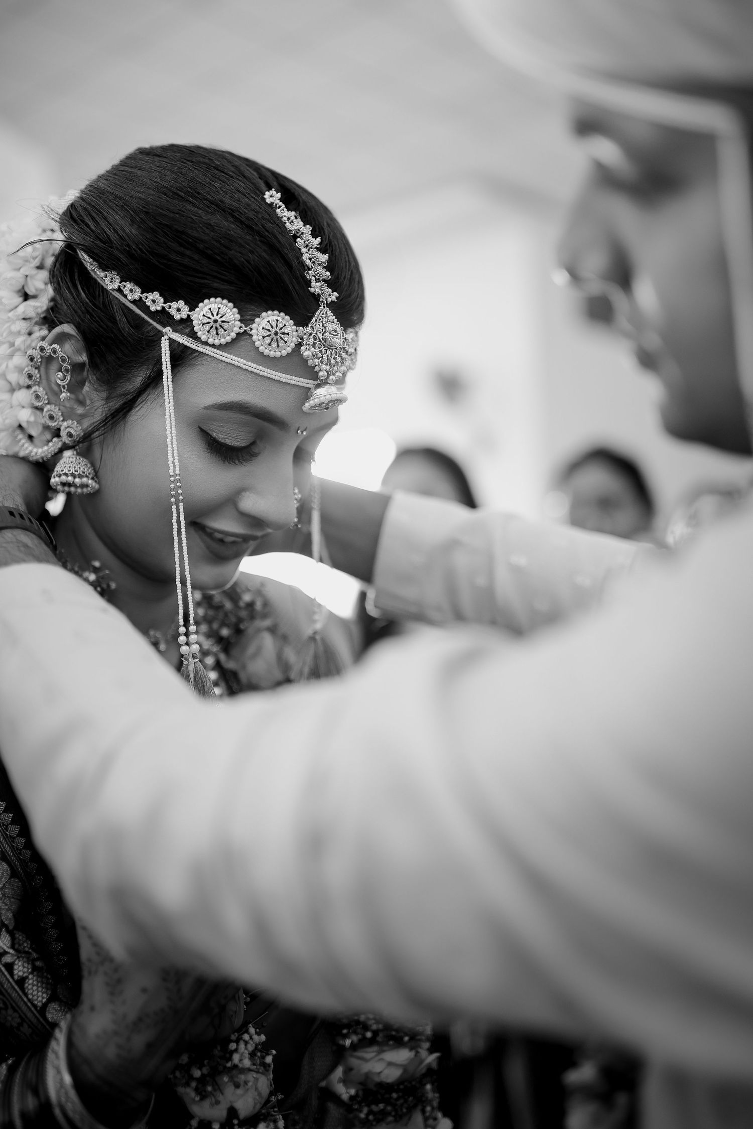 Black and white close-up shots of a bride getting ready with traditional Indian bridal jewelry and makeup.