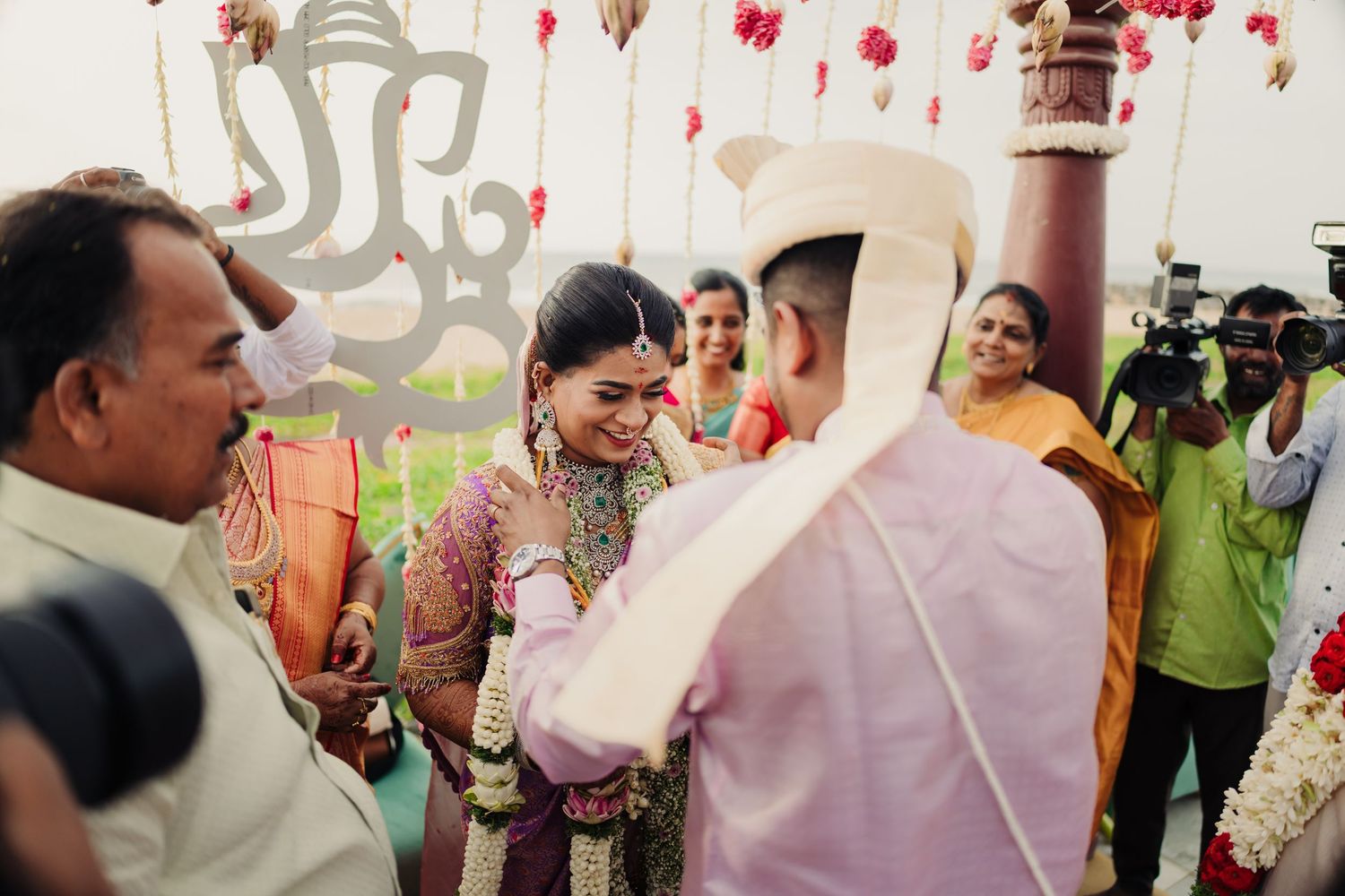 Wedding celebration with guests gathered under decorative pink floral arrangements.