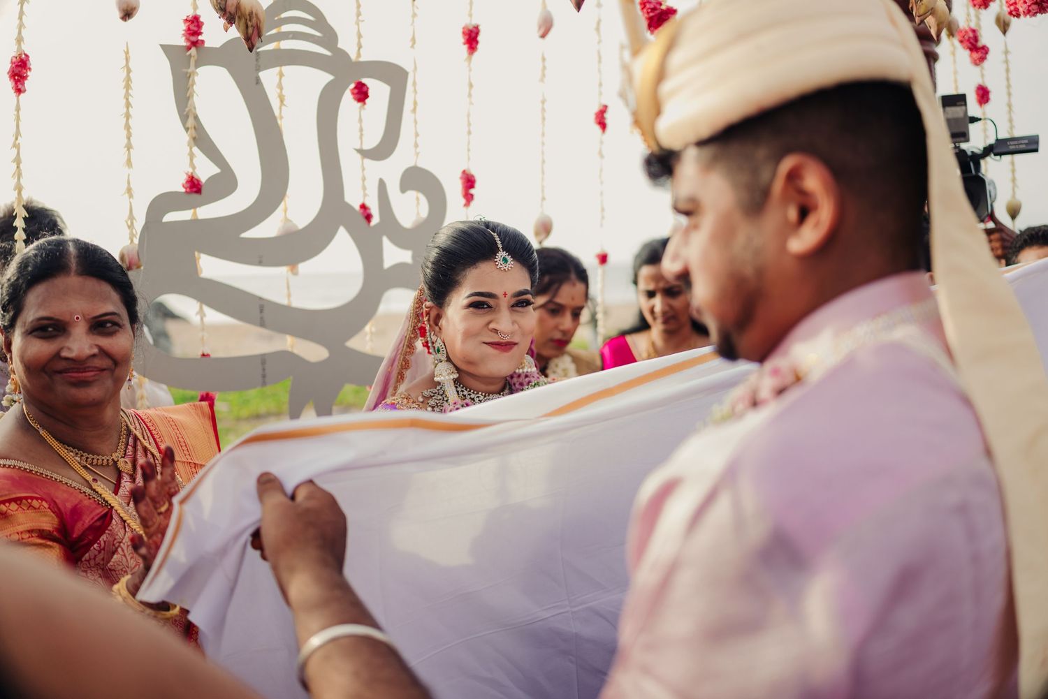 Wedding guests celebrate at an Indian reception with red lanterns and decorative elements hanging from above.