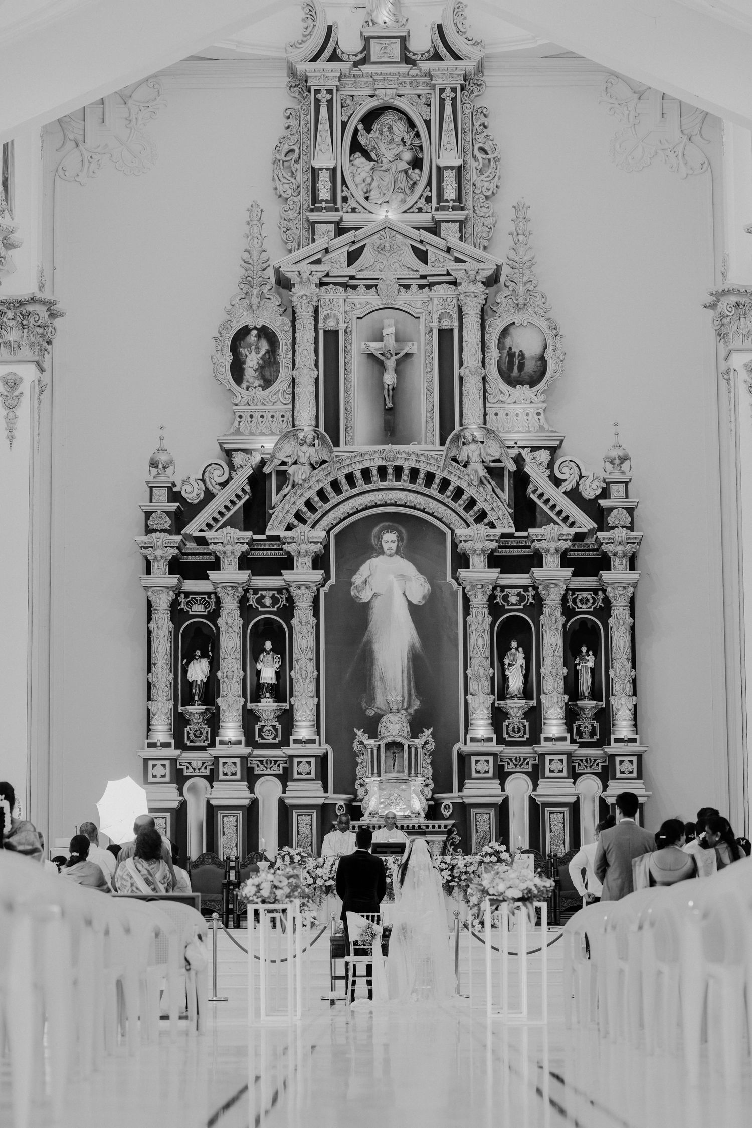 Ornate white church altar with baroque architectural details and religious statues displayed in symmetrical arrangement.